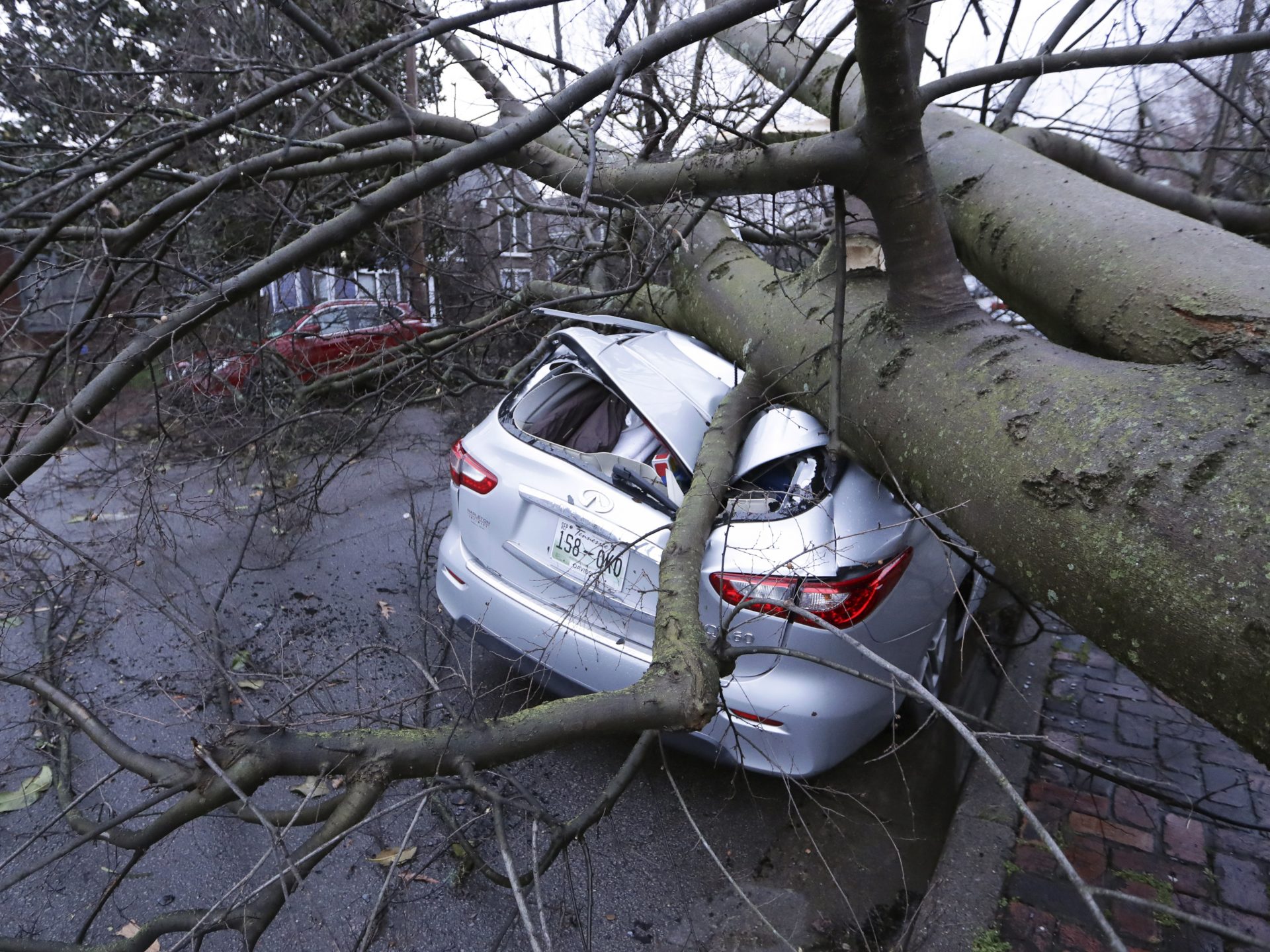 A car crushed by a tree sits on a street after a tornado touched down Tuesday, in Nashville, Tenn.