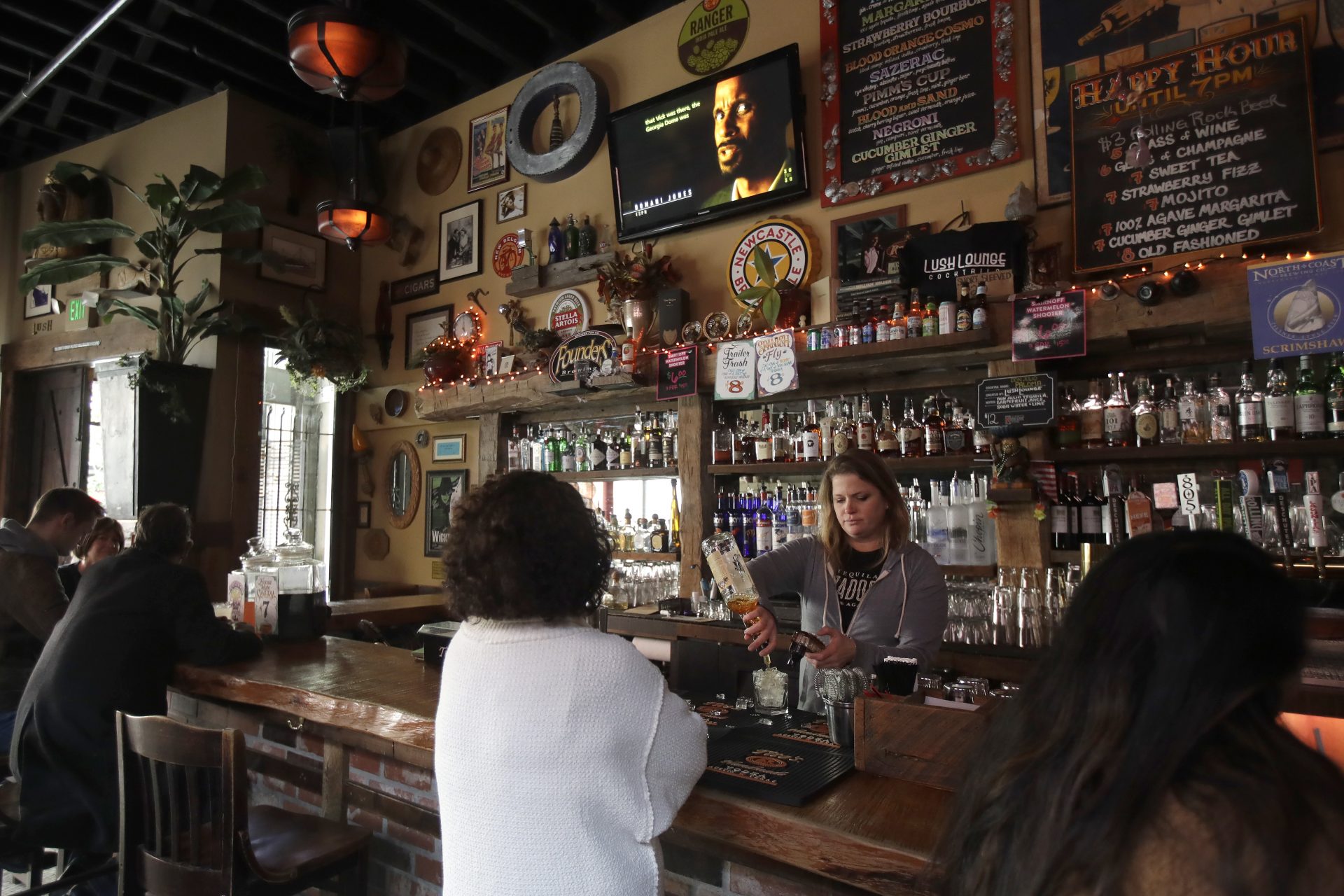 Bartender Lyndsay Przybyl, center rear, pours drinks for customers at Lush Lounge in San Francisco, Sunday, March 15, 2020. California Gov. Gavin Newsom called for all bars, wineries, nightclubs and brewpubs to close in the nation's most populous state and urged seniors and people with chronic health conditions to isolate themselves at home in a bid to contain the spread of the coronavirus.