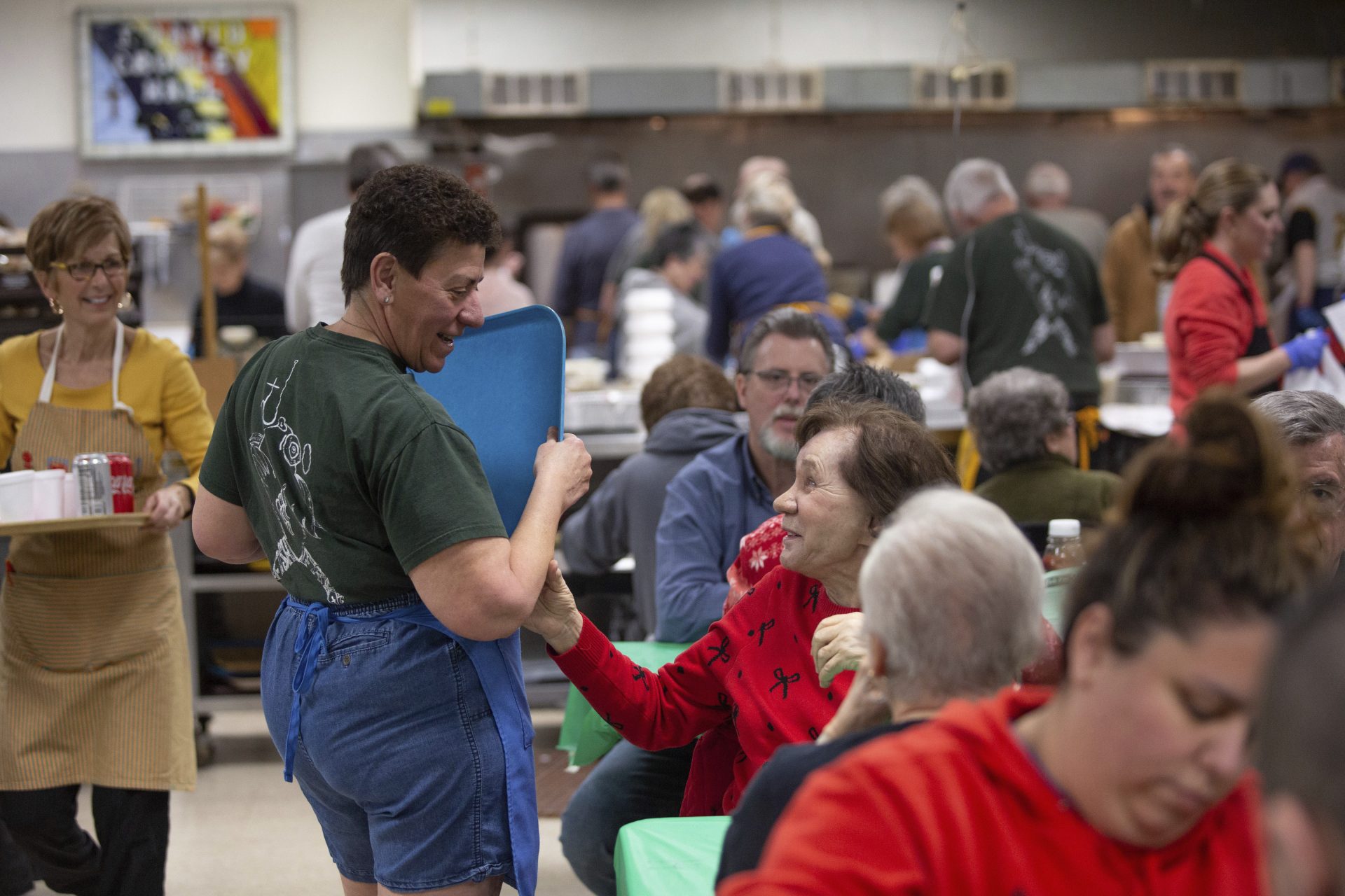 In this Feb. 28, 2020 photo, Ann Painter, center, is greeted by a diner as she serves meals during the a fish fry at Holy Angels parish in Pittsburgh, Pa. On March 12, Pittsburgh Bishop David Zubik suggested that people enjoy the fish fries with a take-out order rather than dining in due to virus concerns.