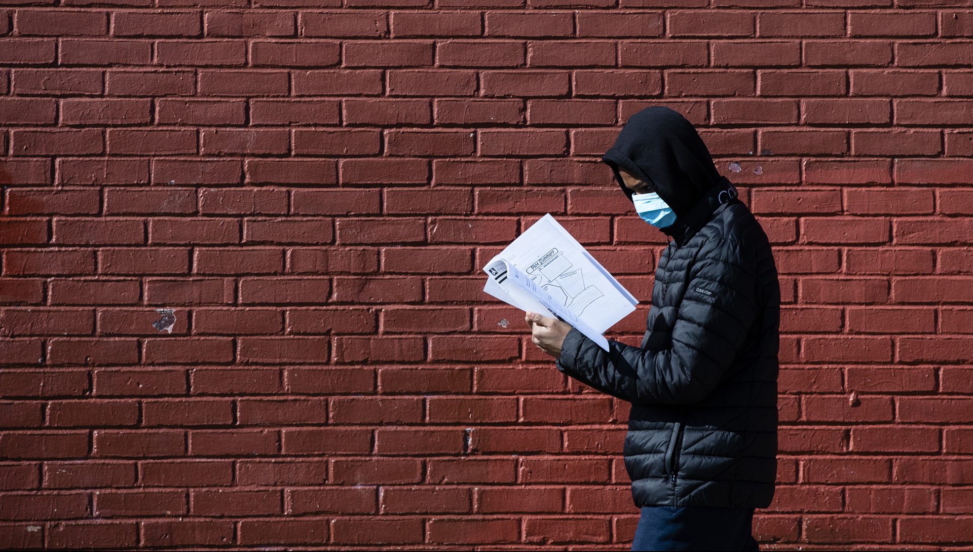 Terrell Bell, wearing a protective face mask, looks at a learning guide he picked up for his little sister at John H. Webster Elementary School in Philadelphia, Thursday, March 26, 2020. Gov. Tom Wolfâ€™s administration reported more new coronavirus-related deaths in Pennsylvania on Wednesday. Residents are ordered to stay home, with few exceptions.