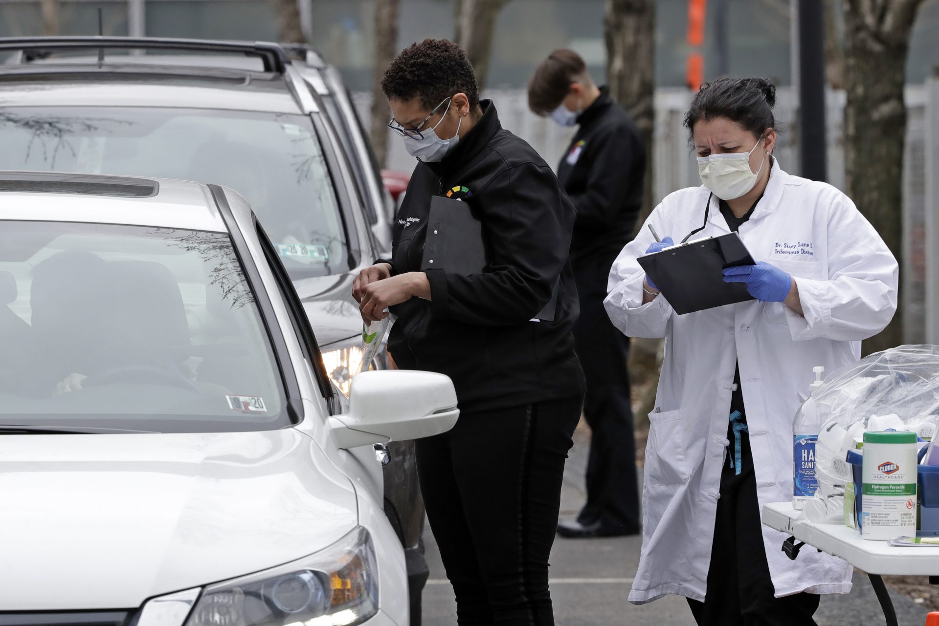 Cars line up outside the Central Outreach Wellness Center on the Northside of Pittsburgh, Monday, March 16, 2020, for drive-by testing for COVID-19. The testing, that is limited to 100 kits at present, is being done in partnership with Quest Diagnostics, one of the commercial laboratory companies that have offered COVID-19 tests to dramatically increase the nation's capability. Central Outreach Medical Director Dr. Stacy Lane said the drive-by testing is being used to not contaminate waiting rooms. The testing is based on screening questions for symptoms of dry cough or fever, Central Outreach said.