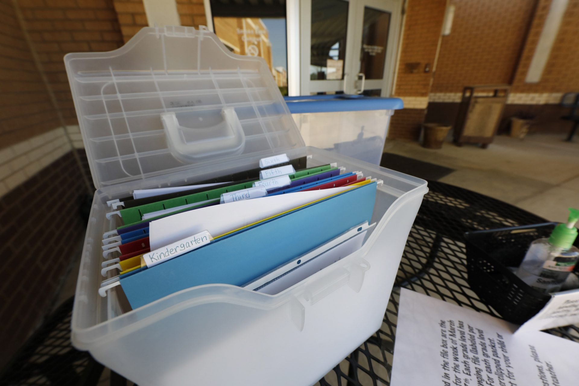 FILE - In this Thursday, March 26, 2020, file photo, grade-appropriate paper homework packets are arranged in a plastic file container awaiting parent pickup at the front of the Oakdale Elementary School in Brandon, Miss. Because of the fear of spreading the new coronavirus, schools have suspended on-site classes and are dealing with the new world of online teaching while trying to provide educational materials to those students who do not possess computers or smartphones with data capability, have limited or no internet service or simply live in a rural locale with a school that has limited digital options.