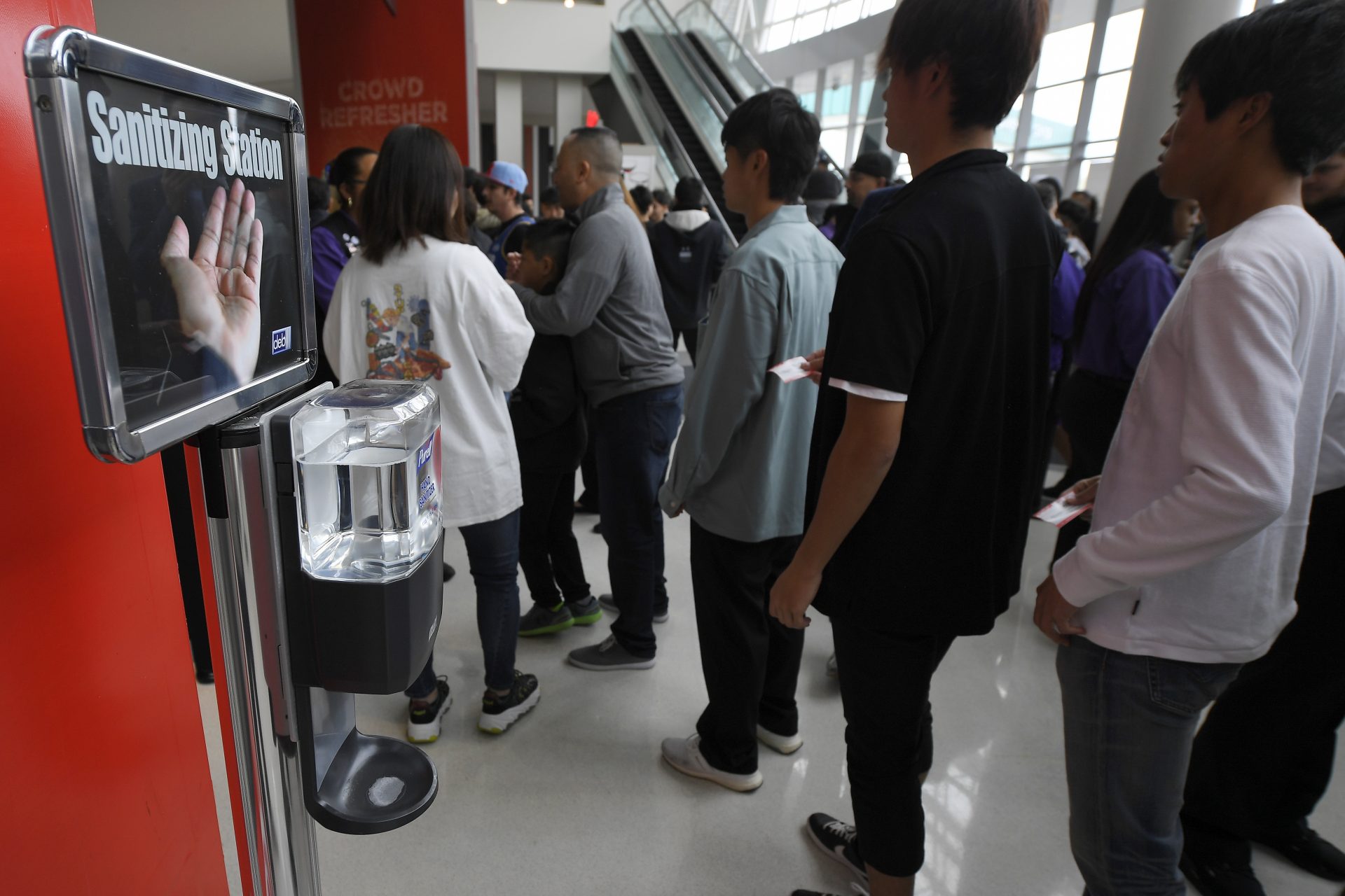 Fans walk by a sanitizing station at Staples Center prior to an NBA basketball game between the Los Angeles Clippers and the Philadelphia 76ers Sunday, March 1, 2020, in Los Angeles.