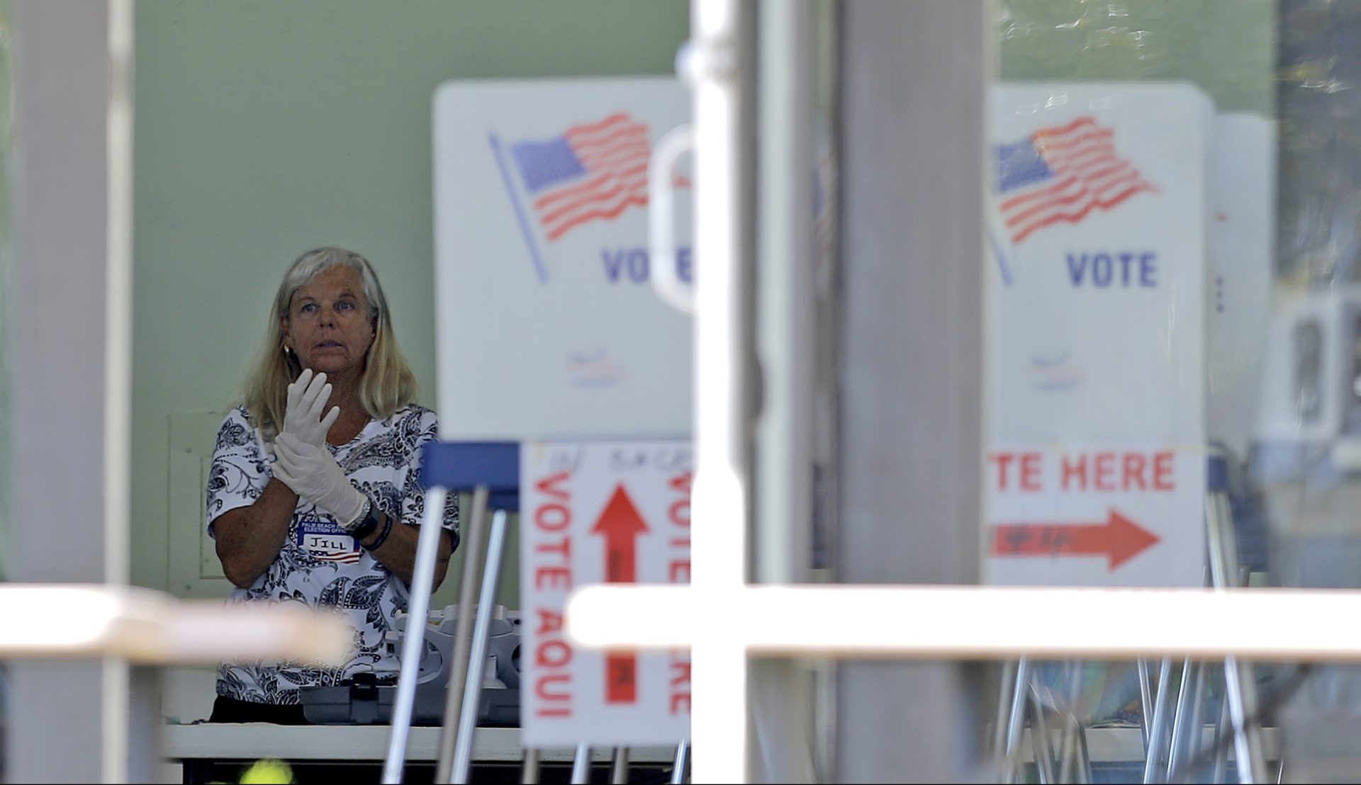 A polling place worker adjusts gloves as she tends to a reception table during the Florida primary election at the First United Methodist Church, Tuesday, March 17, 2020, in Jupiter, Fla. As Florida officials try to contain the spread of the novel coronavirus, the state's voters headed to the polls to cast ballots in the Democratic presidential primary.