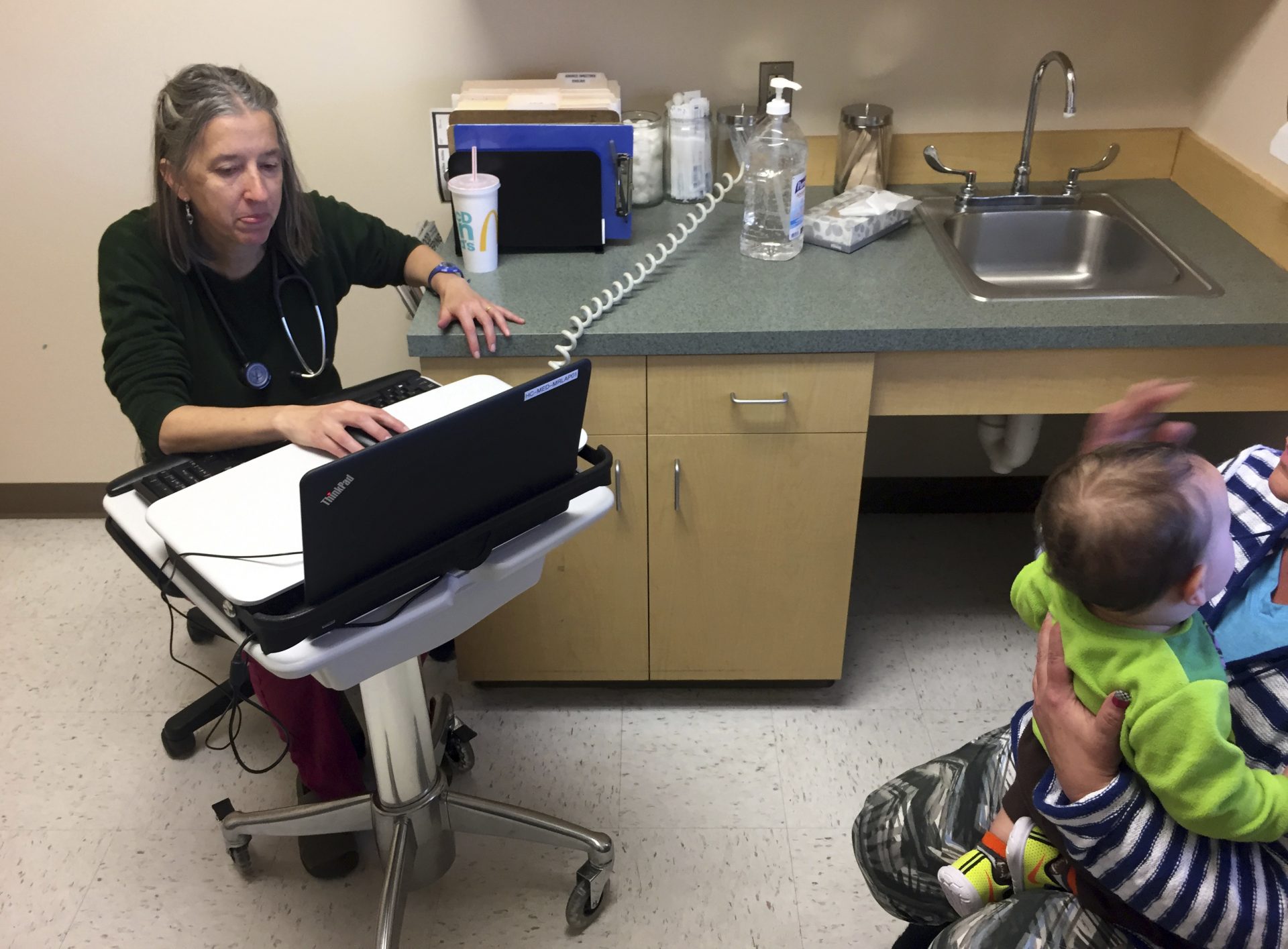 In this Dec. 21, 2016 photo, family physician Leslie Hayes attends to a 31-year-old mother (right, partially obscured) who is being treated for an addiction to heroin with the anti-craving medication Subutext, at the El Centro Family Health medical clinic in Espanola, N.M. Hayes credits her ability to effectively treat opioid addiction disorders to a training and mentoring program known as Project ECHO that is being tapped by federal officials for possible broader applications.