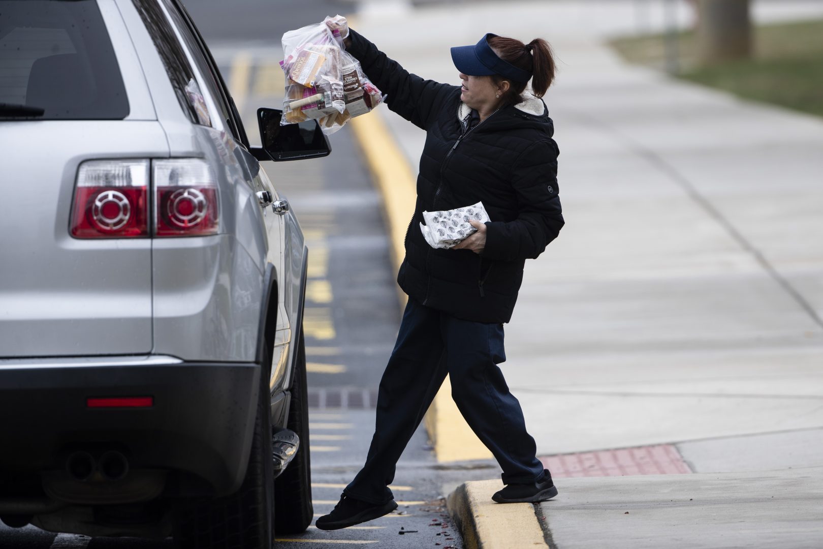 Cafeteria worker Cathy Piluso hands out free meals at Bensalem High School in Bensalem, Pa., Thursday, March 19, 2020. Pennsylvania reported another big jump in confirmed coronavirus Thursday. The state Department of Health reported that cases topped 180, up 40%.  
