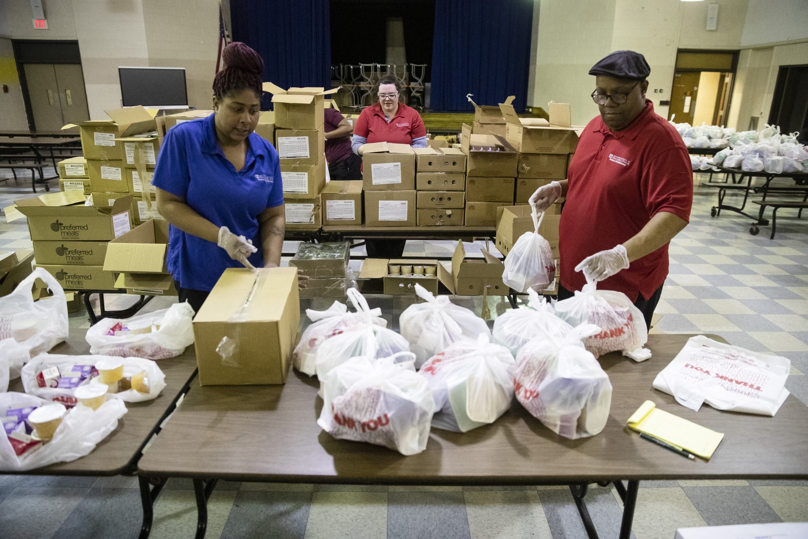 School staff pack grab-and-go meals for distribution to students and families at John H. Webster Elementary School in Philadelphia, Wednesday, March 25, 2020. 