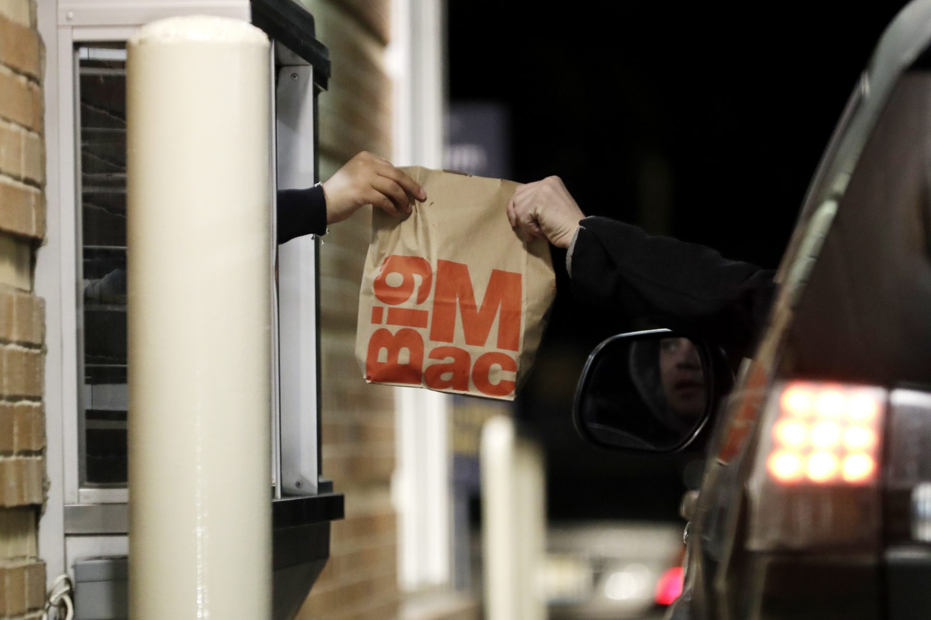 A customer, right, picks up his food at a McDonald in Wheeling, Ill., Sunday, March 15, 2020. Illinois Gov. J.B. Pritzker on Sunday ordered all bars and restaurants in the state to close starting Monday night, March 16 through March 30.