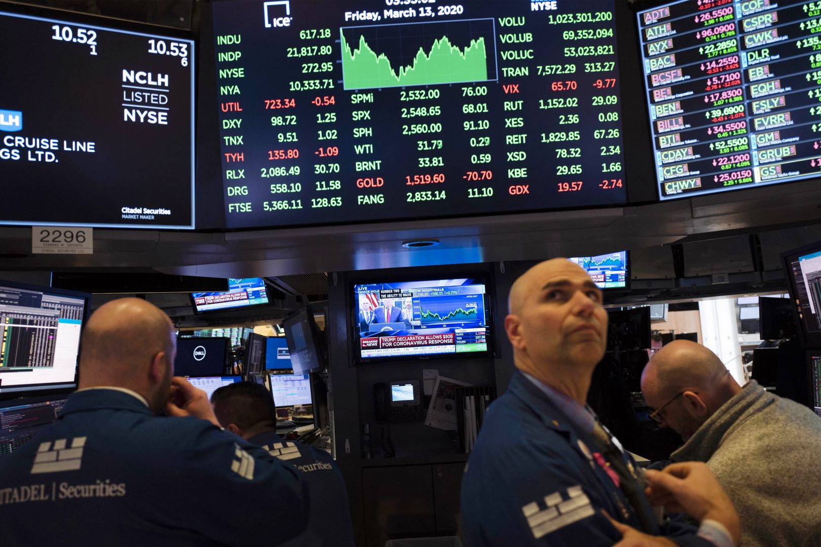 Traders listen at the New York Stock Exchange to President Donald Trump's televised speech from the White House, Friday, March 13, 2020, in New York. (AP Photo/Mark Lennihan)