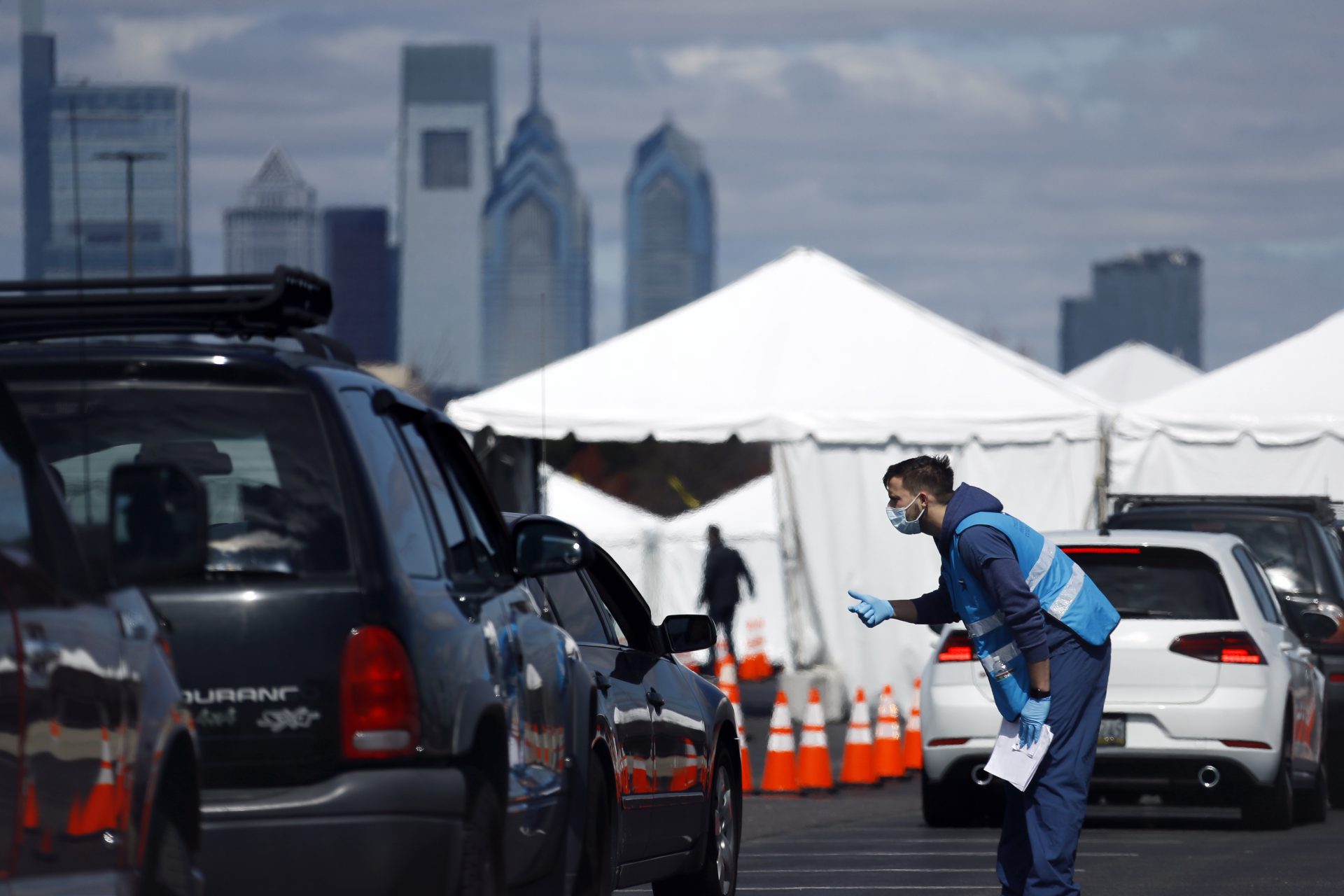 A healthcare worker talks with a patient at a COVID-19 testing site near Citizens Bank Park, home of the Philadelphia Phillies baseball team, Tuesday, March 24, 2020, in Philadelphia. For most people, the new coronavirus causes only mild or moderate symptoms. For some it can cause more severe illness.