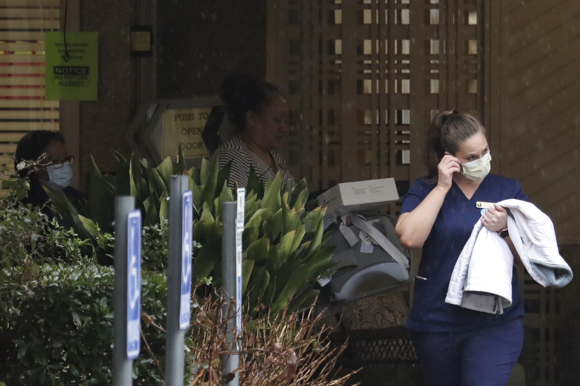 A worker at the Life Care Center in Kirkland, Wash., near Seattle, wears a mask as she leaves the building, Monday, March 2, 2020. Several of the people who have died in Washington state from the COVID-19 coronavirus were tied to the long-term care facility, where dozens of residents were sick.