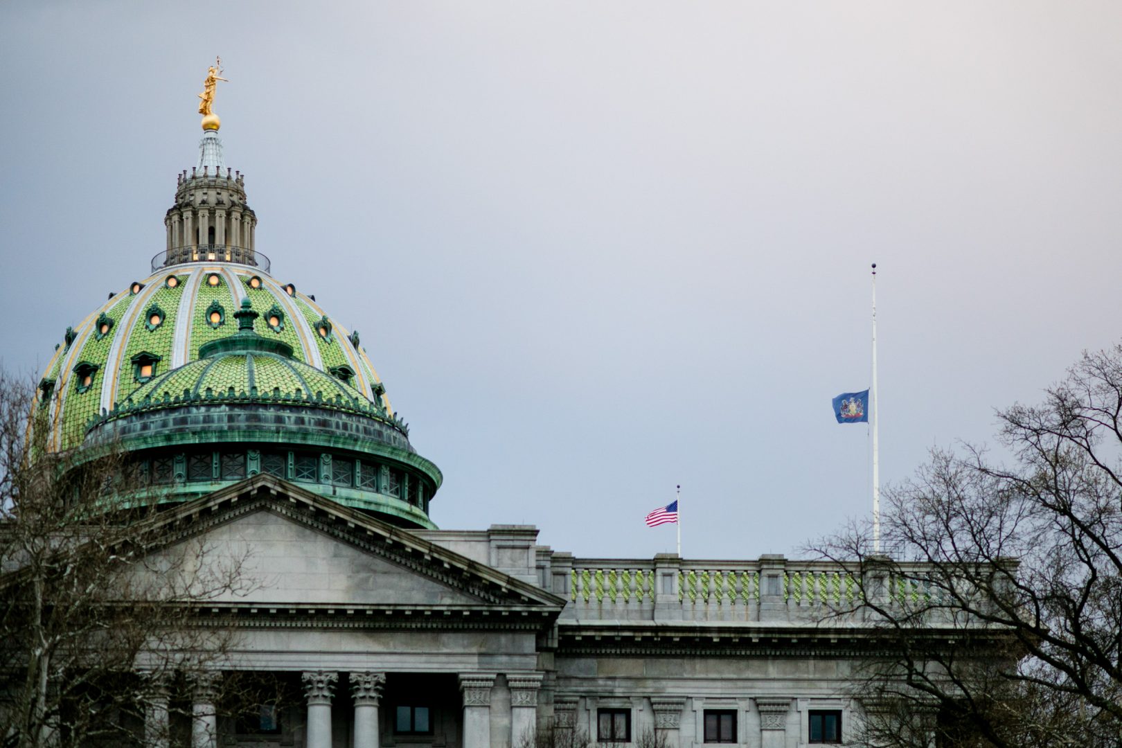 The American and Pennsylvania flags over the capitol building in Harrisburg on April 7, 2020. Gov. Tom Wolf ordered the state flag to fly at half staff to honor victims of the coronavirus outbreak.