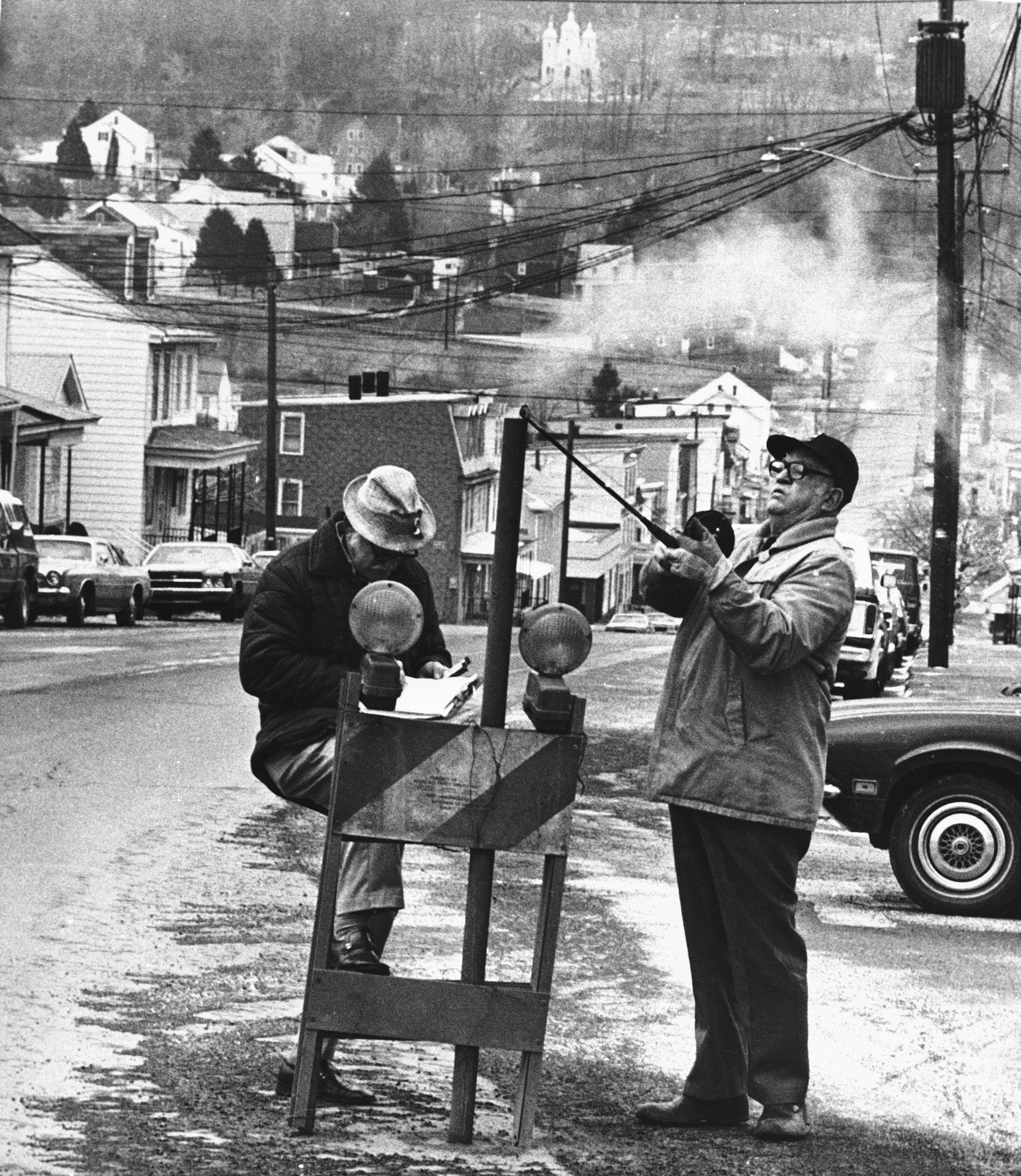 U.S. Bureau of Mines' John Stockalis, right, and Dan Lewis drop a thermometer through a hole on Main Street in Centralia, Pennsylvania on April 2, 1981, to measure the heat from a mine shaft blaze that has burned for 19 years. Townspeople will vote on May 19 to decide if the town should be relocated so the fire can be dug out.