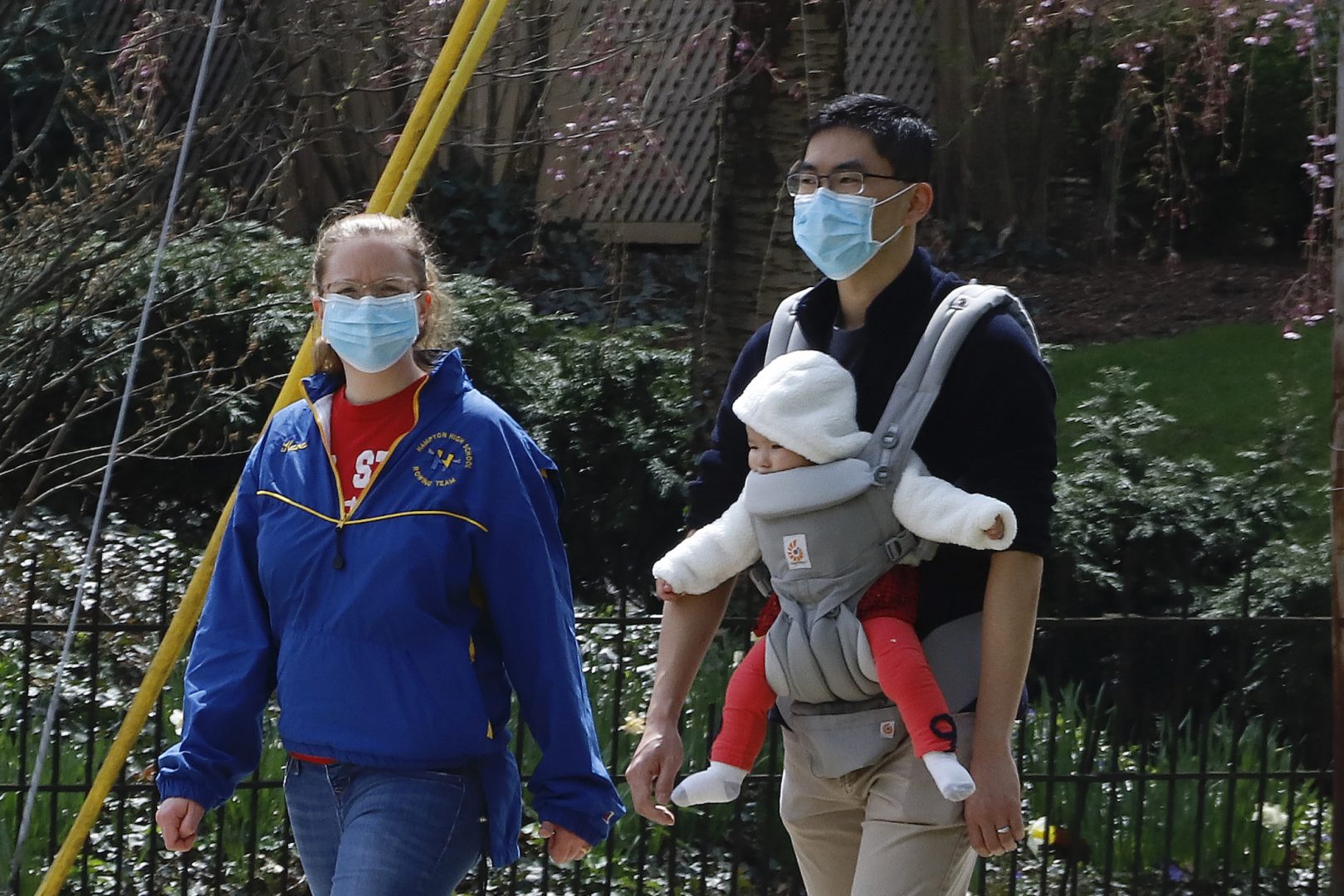 A couple out for walk wear protective masks on a warm afternoon in Pittsburgh, Sunday, April 5, 2020. (AP Photo/Gene J. Puskar)