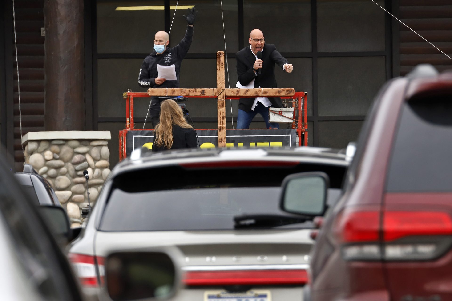 Pastor Bruce Schafer, top right, preaches from a scissor lift during the first of two drive-in Easter services held by Grace Life Church in a parking lot in Monroeville, Pa., Sunday, April 12, 2020.