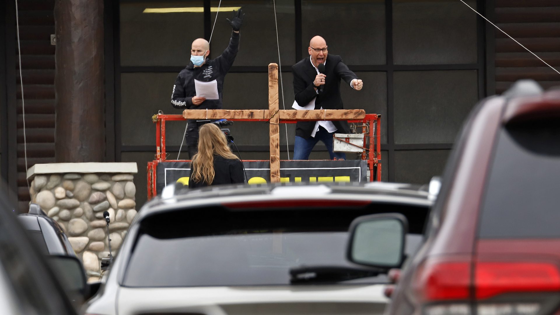 Pastor Bruce Schafer, top right, preaches from a scissor lift during the first of two drive-in Easter services held by Grace Life Church in a parking lot in Monroeville, Pa., Sunday, April 12, 2020.