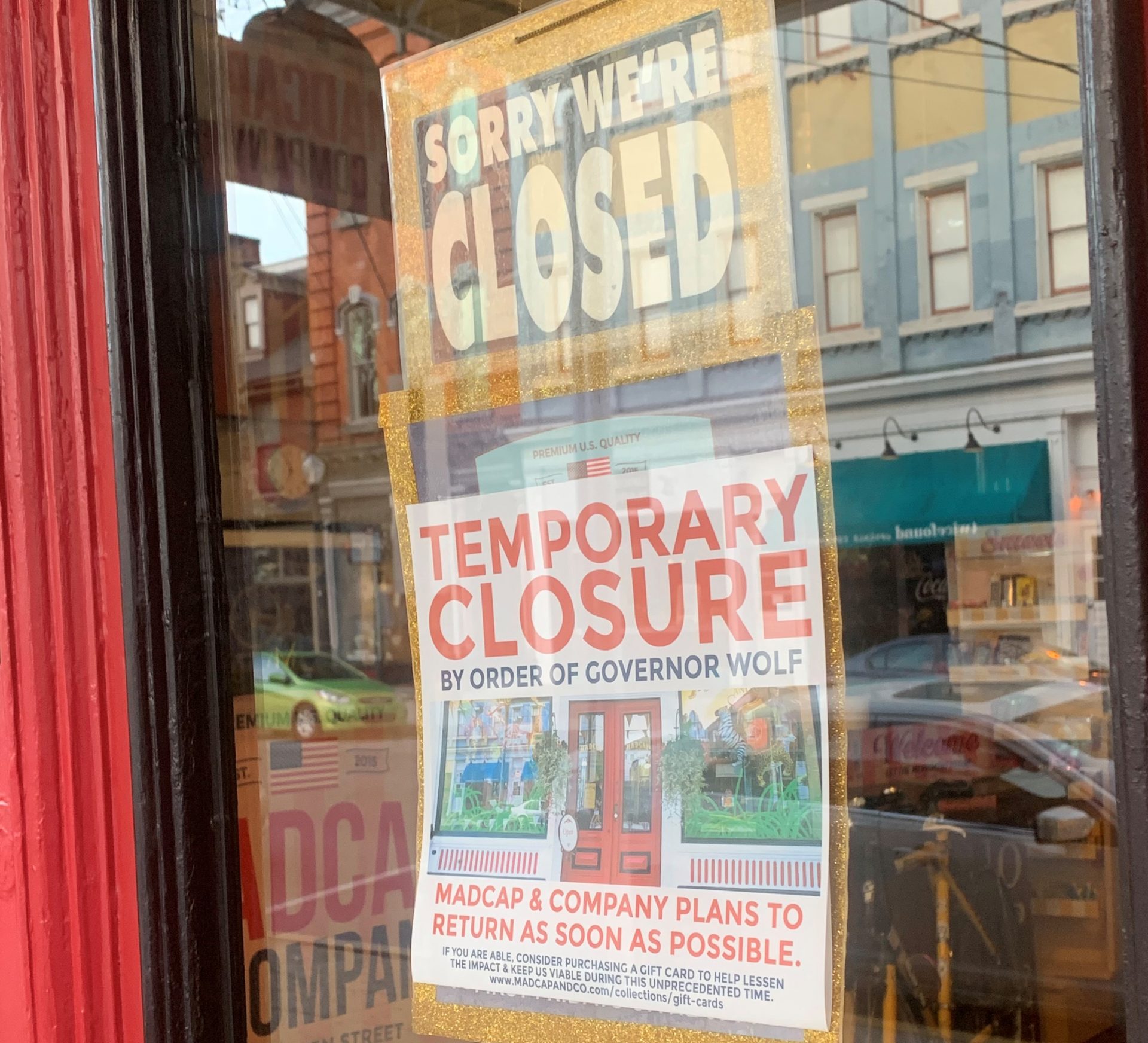 A sign hangs in the door of Madcap & Company, a novelty store in Lancaster, Pa.