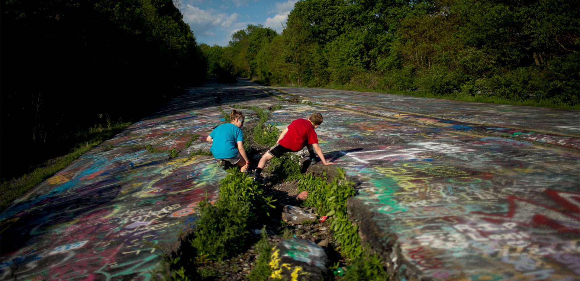 People explore "Grafitti Highway," an abandoned piece of Route 61 just south of Centralia, on May 24, 2016. The mine fire posed a real threat to the structural integrity of it. Subsidence was leading to uneven surfaces and steam poured out through cracks in the asphalt. Today the abandoned section of Route 61 is a favorite location for tourists.