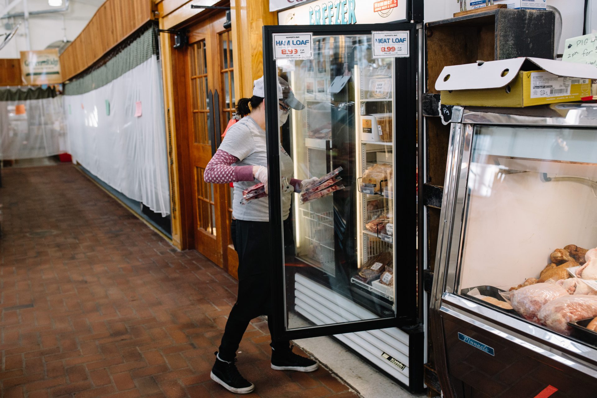 A worker wearing a mask stocks meat in a freezer at Broad Street Market in Harrisburg on April 10, 2020. The market is much quieter since the coronavirus pandemic effectively shut down the region.