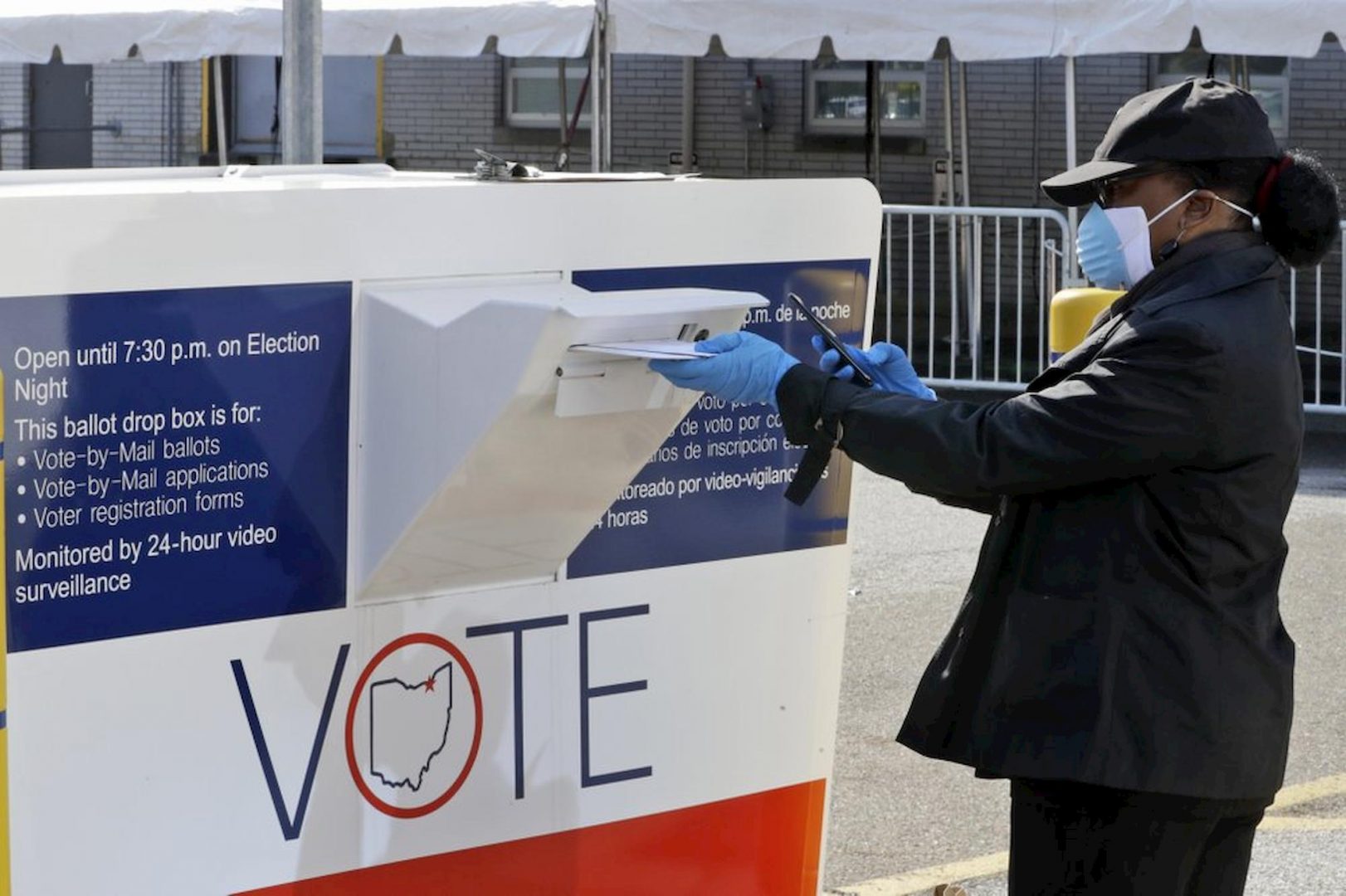 Marcia McCoy drops her ballot into a box outside the Cuyahoga County Board of Elections in Cleveland, Ohio, Tuesday. The first major test of an almost completely vote-by-mail election during a pandemic is unfolding in Ohio, offering lessons to other states about how to conduct one of the most basic acts of democracy amid a health crisis. 
