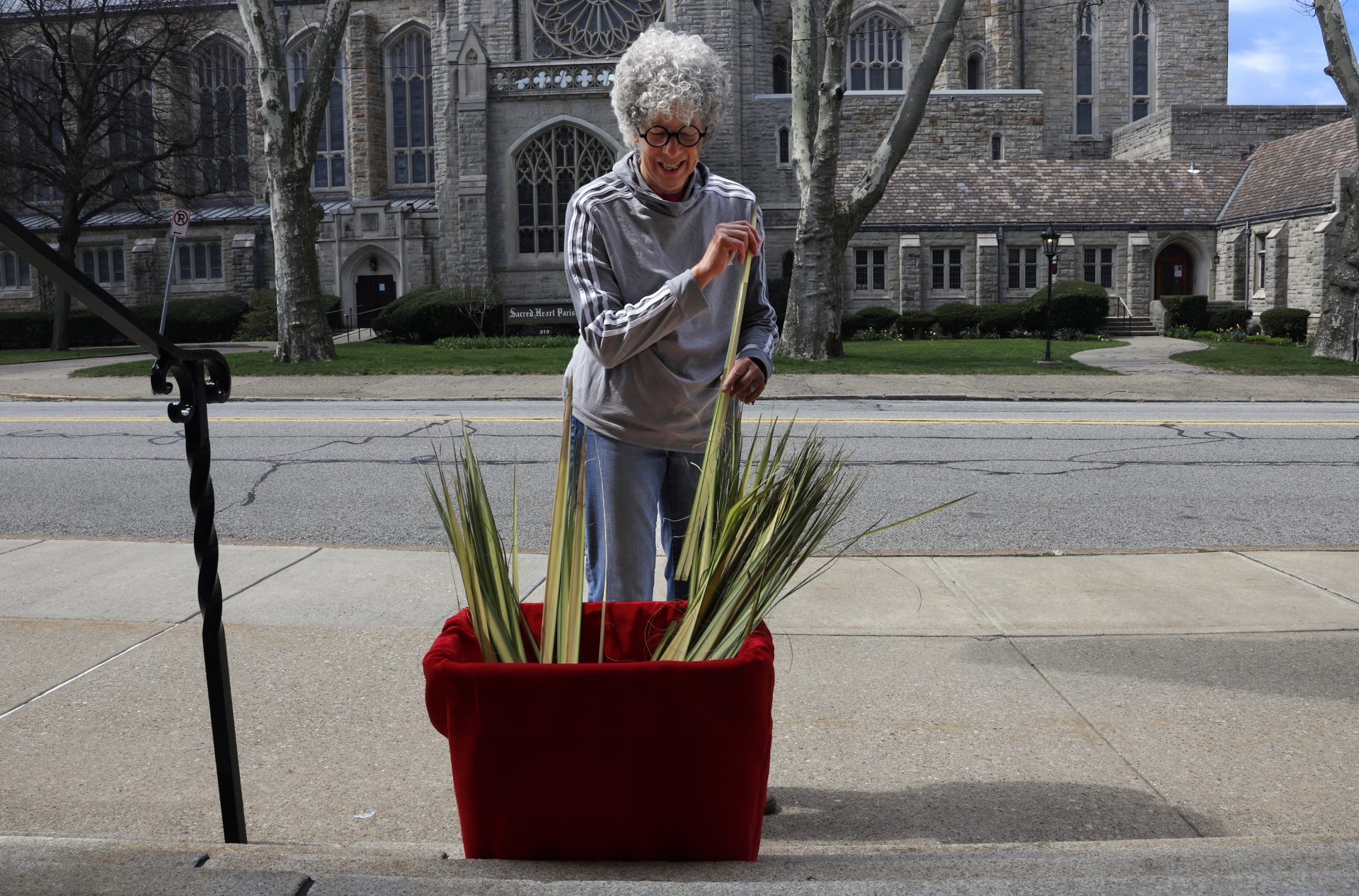 Joanna Schultz, a member of the choir at Calvary Episcopal Church, picks up her palms from a container on the steps outside the church on Palm Sunday, April 5, 2020 in Pittsburgh. As part of the statewide effort to mitigate the spread of COVID-19, the church is closed, and offering online streaming of services.