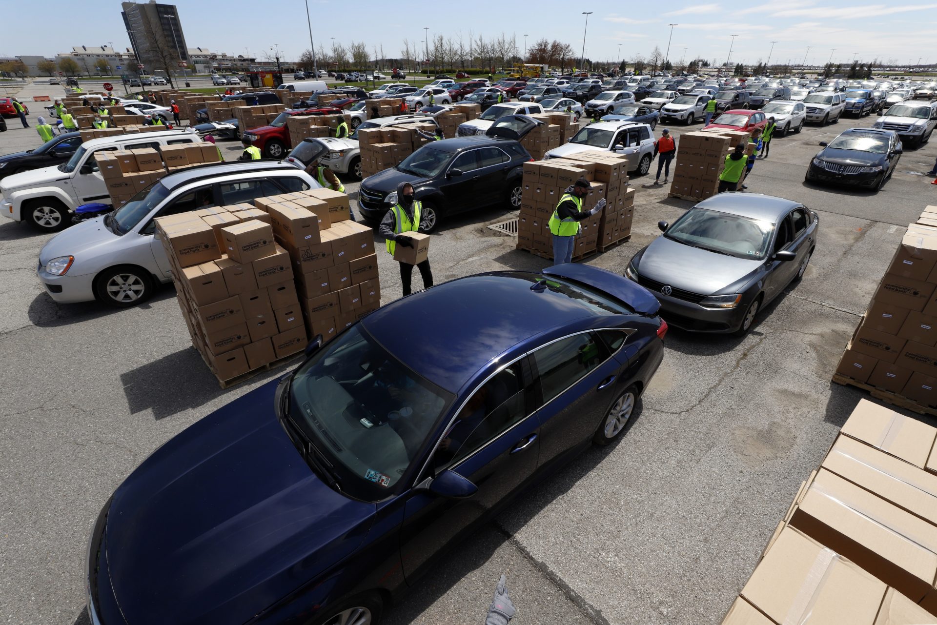 Using part of the Pittsburgh International Airport parking lot, that has been left vacant by the COVID-19 pandemic, volunteers from the Greater Pittsburgh Community Food Bank, load boxes of food into cars during a drive-up food distribution, Wednesday, April 22, 2020.