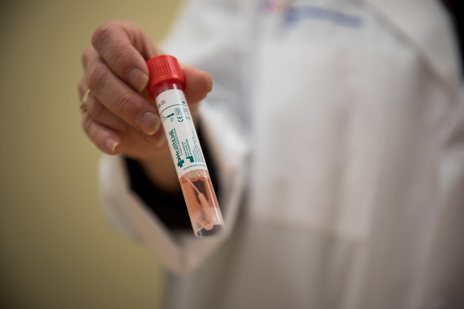 A pathologist holds a vial from a COVID-19 test kit. Various bottlenecks in the U.S. that have constrained widespread testing for the coronavirus were problems in February and persist today.