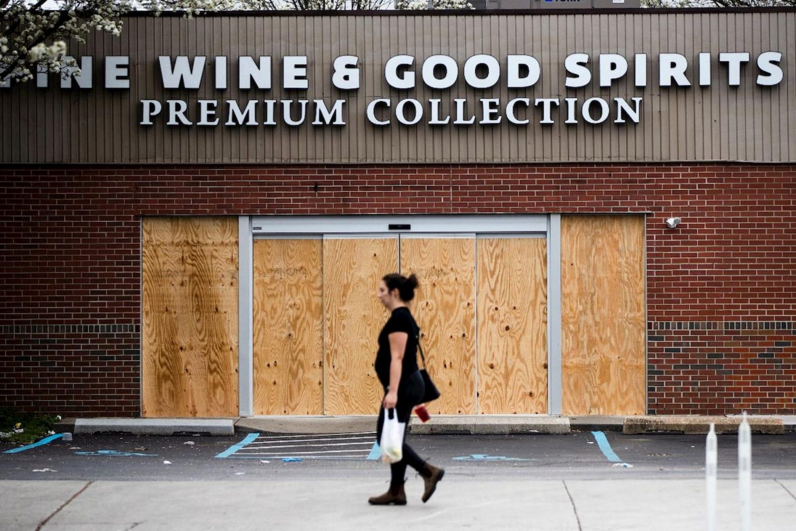 A pedestrian walks past a boarded up Wine and Spirits store in Philadelphia, Friday, March 20, 2020.