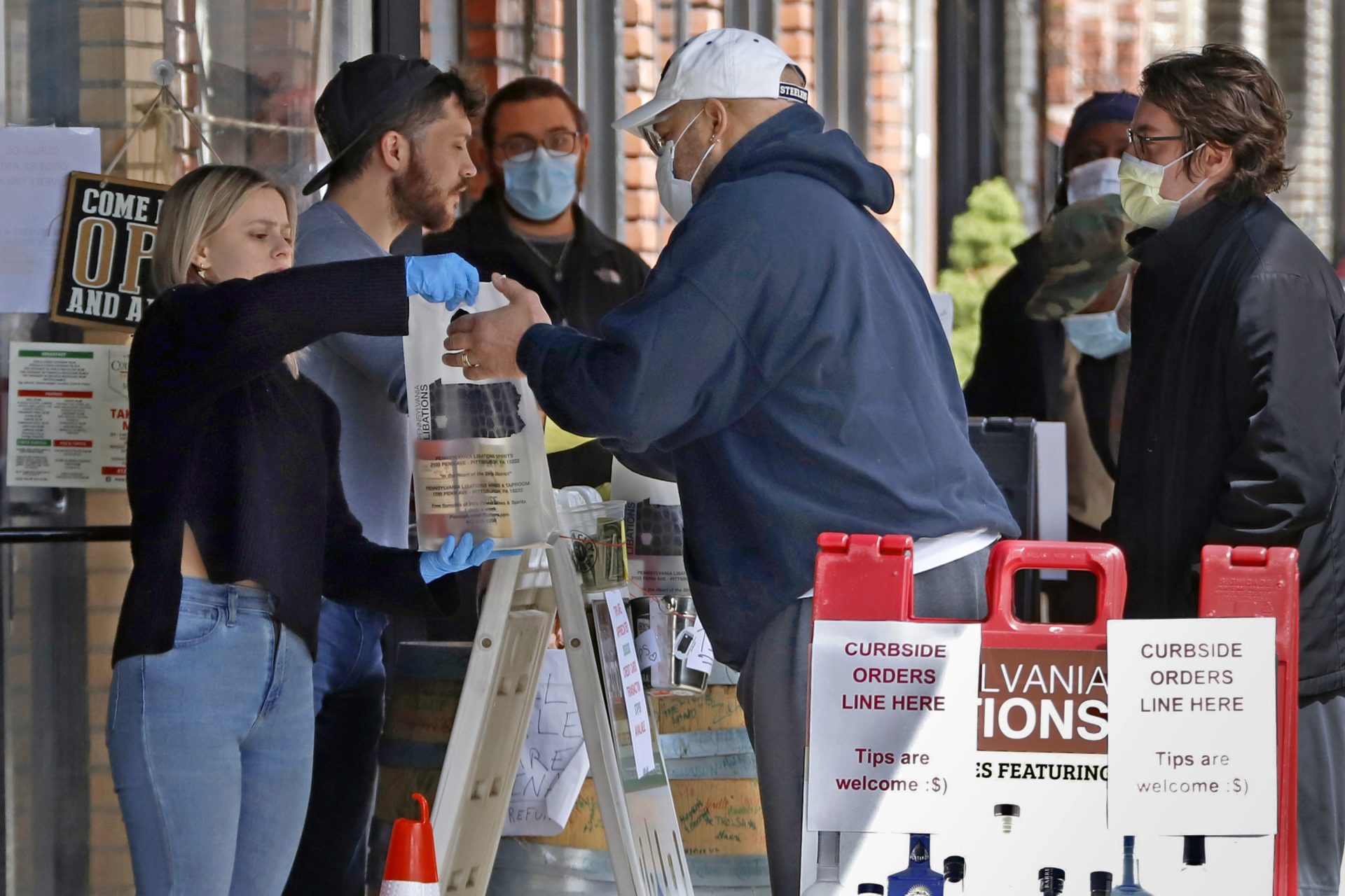 In this April 16, 2020 photo people line up to purchase Pennsylvania made liquor at Pennsylvania Libations in Pittsburgh's Strip District. The Pennsylvania liquor control board closed the Pennsylvania state-owned stores that retail nearly all of Pennsylvania's liquor in March, driving up demand from the state's distilleries, which have been allowed to continue production and sales, although some report stockpiles are rapidly drying up.