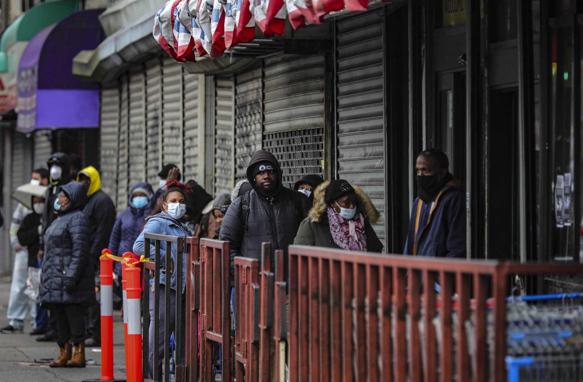 Customers in masks line up outside a grocery store on Flatbush Avenue, waiting to enter after other shoppers have left, because of social distancing efforts during the coronavirus outbreak, Friday April 3, 2020, in New York.