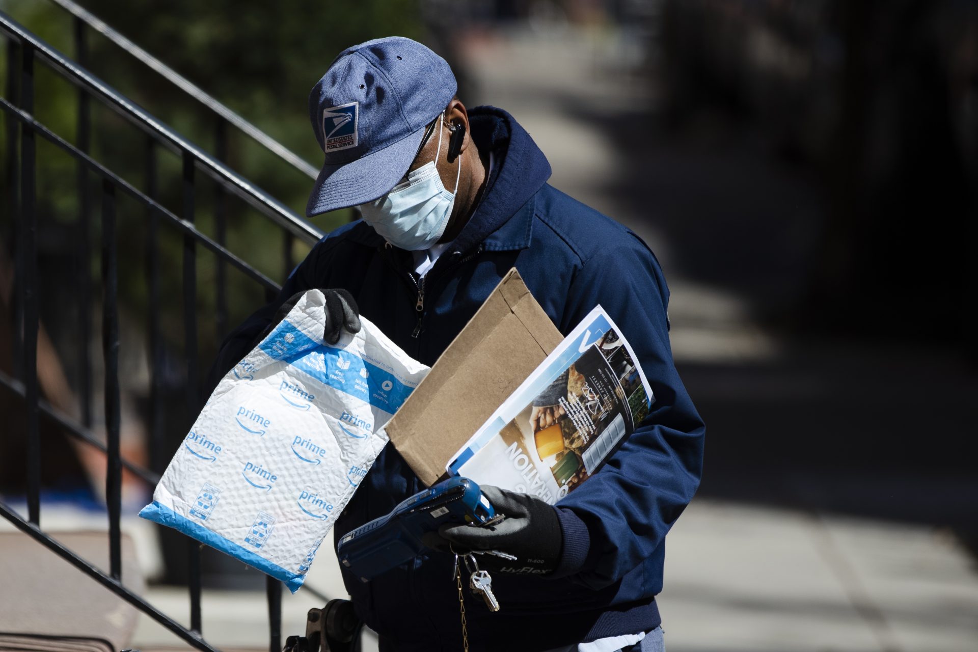A United States Postal worker makes a delivery with gloves and a mask in Philadelphia, Thursday, April 2, 2020. The U.S. Postal Service is keeping post offices open but ensuring customers stay at least 6 feet (2 meters) apart. The agency said it is following guidance from public health experts, although there is no indication that the new coronavirus COVID-19 is being spread through the mail.