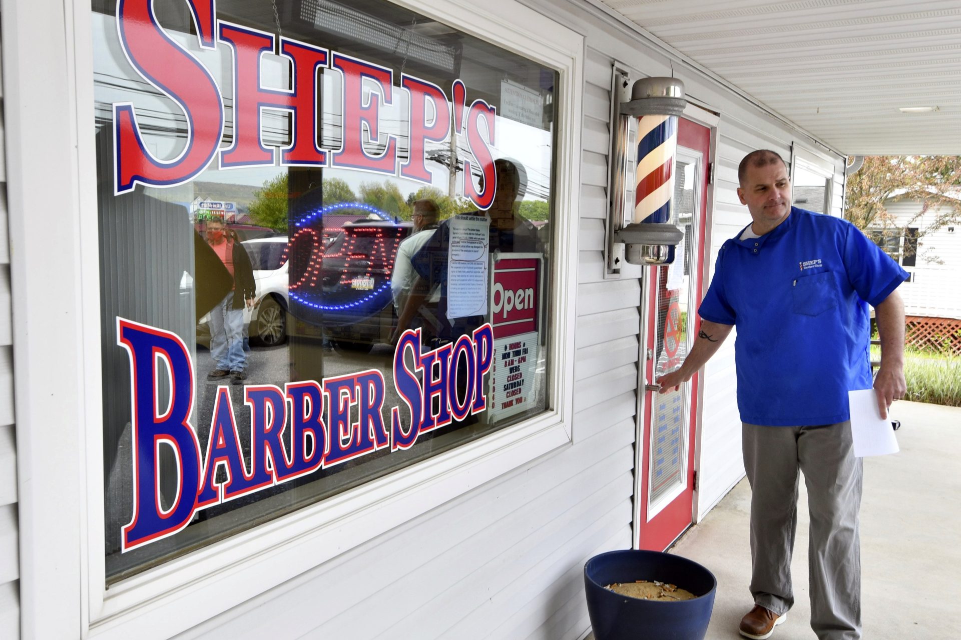 Brad Shepler, a barber who resumed cutting hair despite it being prohibited under Pennsylvania Gov. Tom Wolf's coronavirus shutdown orders, walks out of his barber shop to hold a new conference with local state lawmakers, Thursday, May 14, 2020 in Enola, Pa. Shepler also received a warning letter from the state's licensing agency.