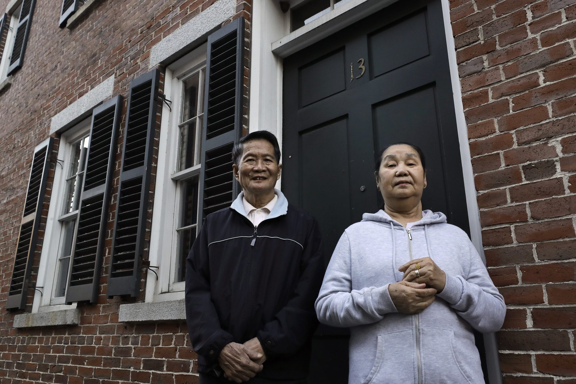 In this Wednesday, May 20, 2020 photo Pay Reh, left, and Poe Meh, right, originally of Burma, also known as Myanmar, stand for a photograph at the entrance to their home, in Lowell, Mass. The elderly couple, who came to Massachusetts as refugees in 2011, were granted a special naturalization oath ceremony in May of 2020 after their lawyer argued that they faced financial hardship if they weren't naturalized immediately.