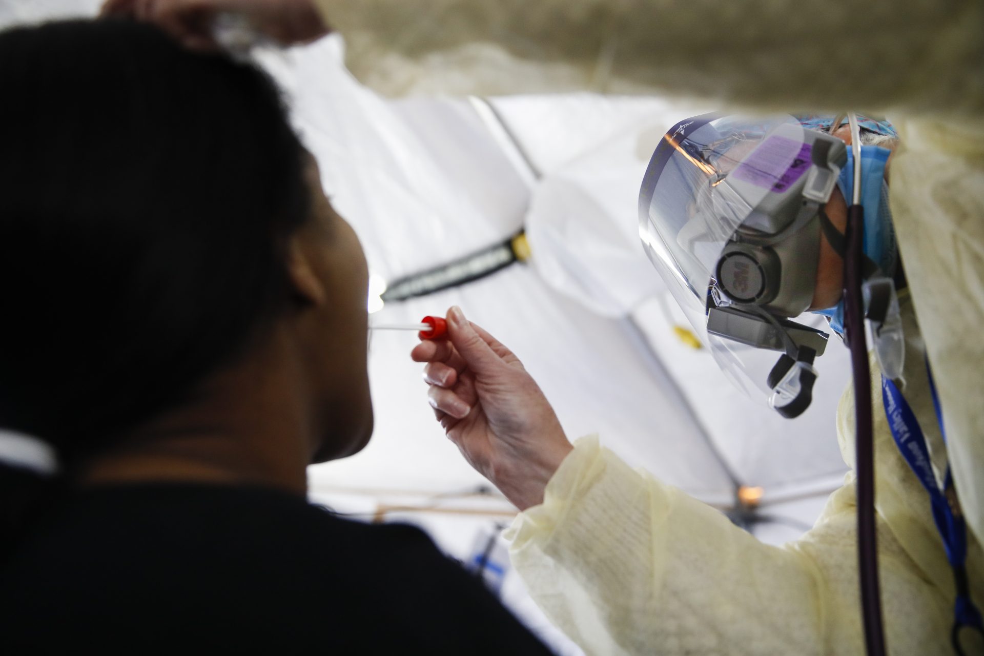 In this April 20, 2020 photo, Catherine Hopkins, Director of Community Outreach and School Health at St. Joseph's Hospital, right, performs a test on a patient in a COVID-19 triage tent at St. Joseph's Hospital in Yonkers, N.Y. New York’s plan for taming the coronavirus hinges on taking a time-tested practice to an extraordinary level: hiring an “army” of people to try to trace everyone who might be infected. It's part of a common approach to controlling infectious diseases -- testing, tracing contacts and isolating those infected. But the scope is staggering even for a public health system that used the technique to combat AIDS and tuberculosis.