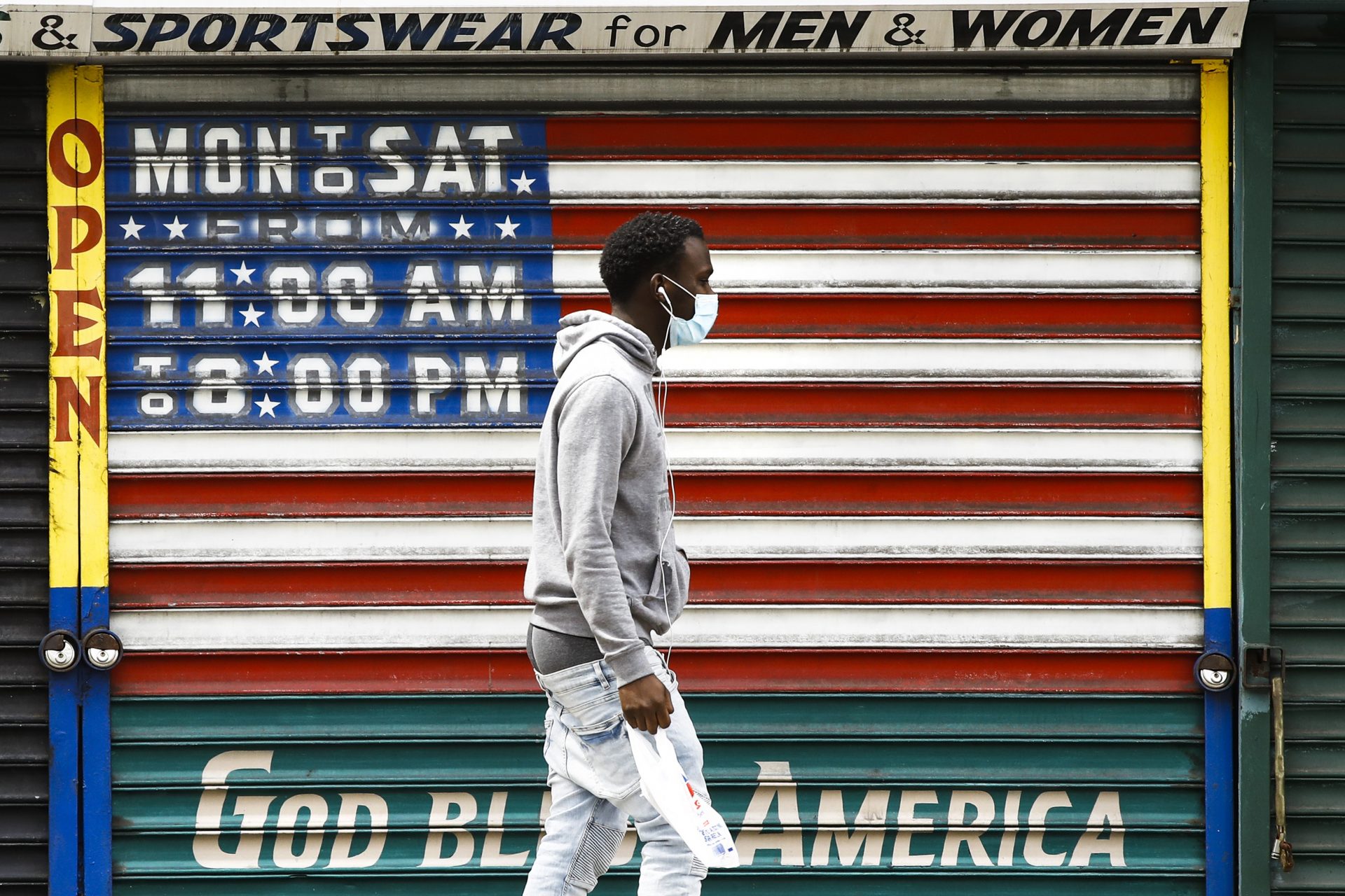 A person wearing a protective face mask as a precaution against the coronavirus walks past a shuttered business in Philadelphia, Thursday, April 23, 2020.