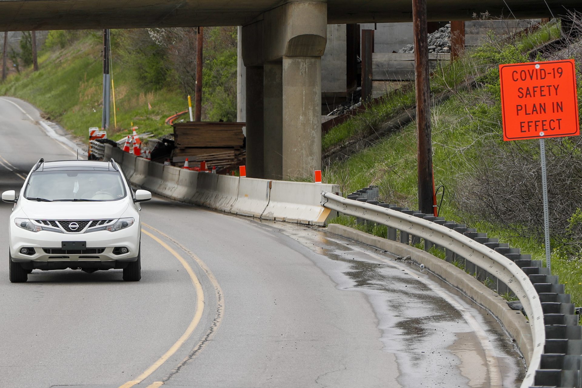 As sign stating "COVID-19 Safety Plan in Effect" marks the approach to the construction zone under an overpass for Interstate 79 as traffic moves through it, in Cranberry Township, Pa., Tuesday, April 28, 2020.