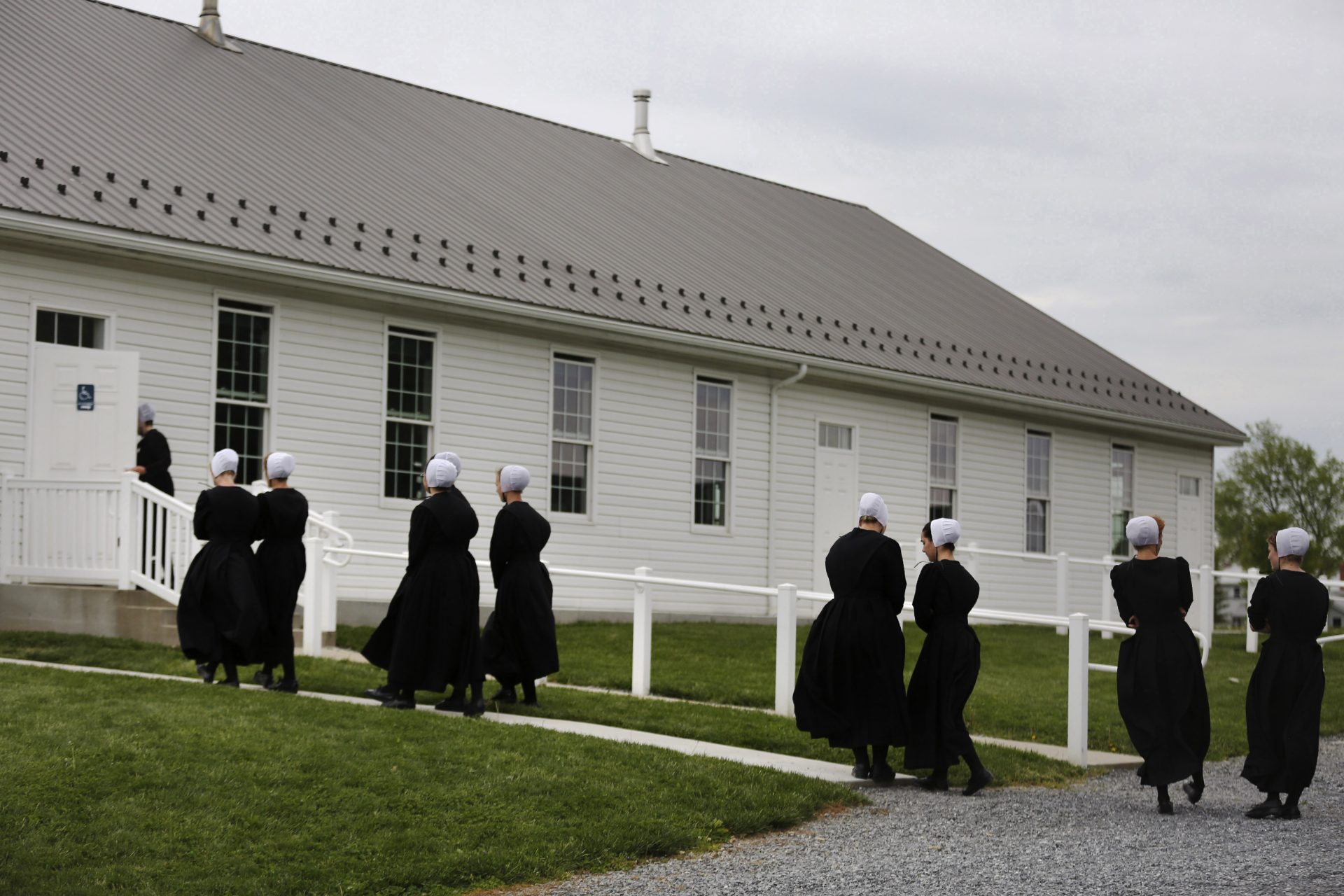 In this Sunday, May 17, 2020, photo, members of the Old Order Stauffer Mennonite Church talk among themselves as they walk into their church for a council meeting with the ministry in New Holland, Pa. Having followed the government's COVID-19 guidelines for nearly two months, the church's more than 200 members gathered for their first in-person service.