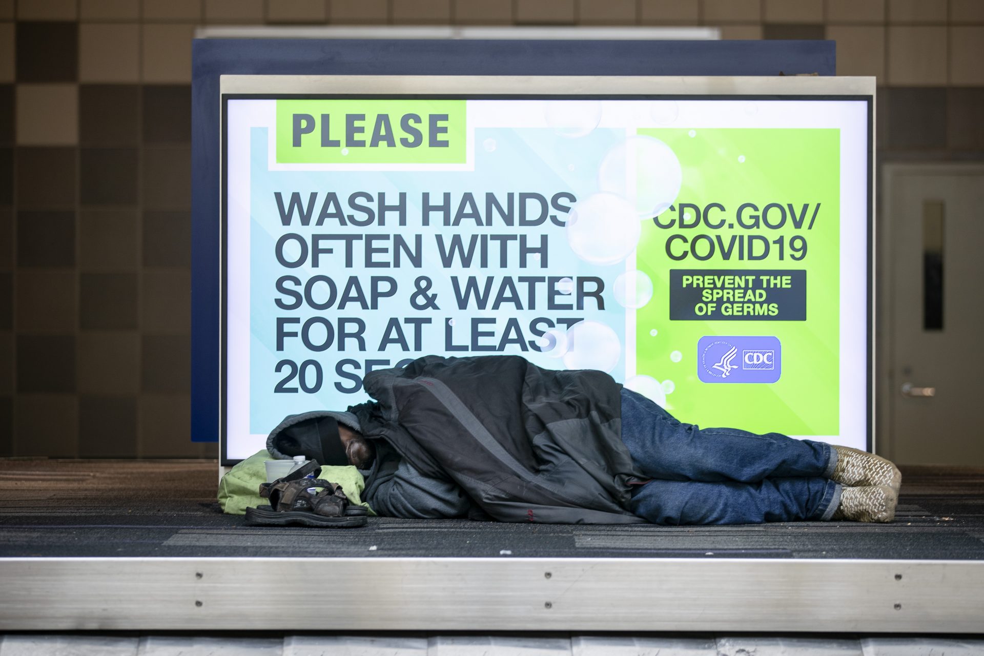 A homeless person sleeps on top of a baggage carousel at Philadelphia International Airport in Philadelphia, Monday, May 25, 2020.