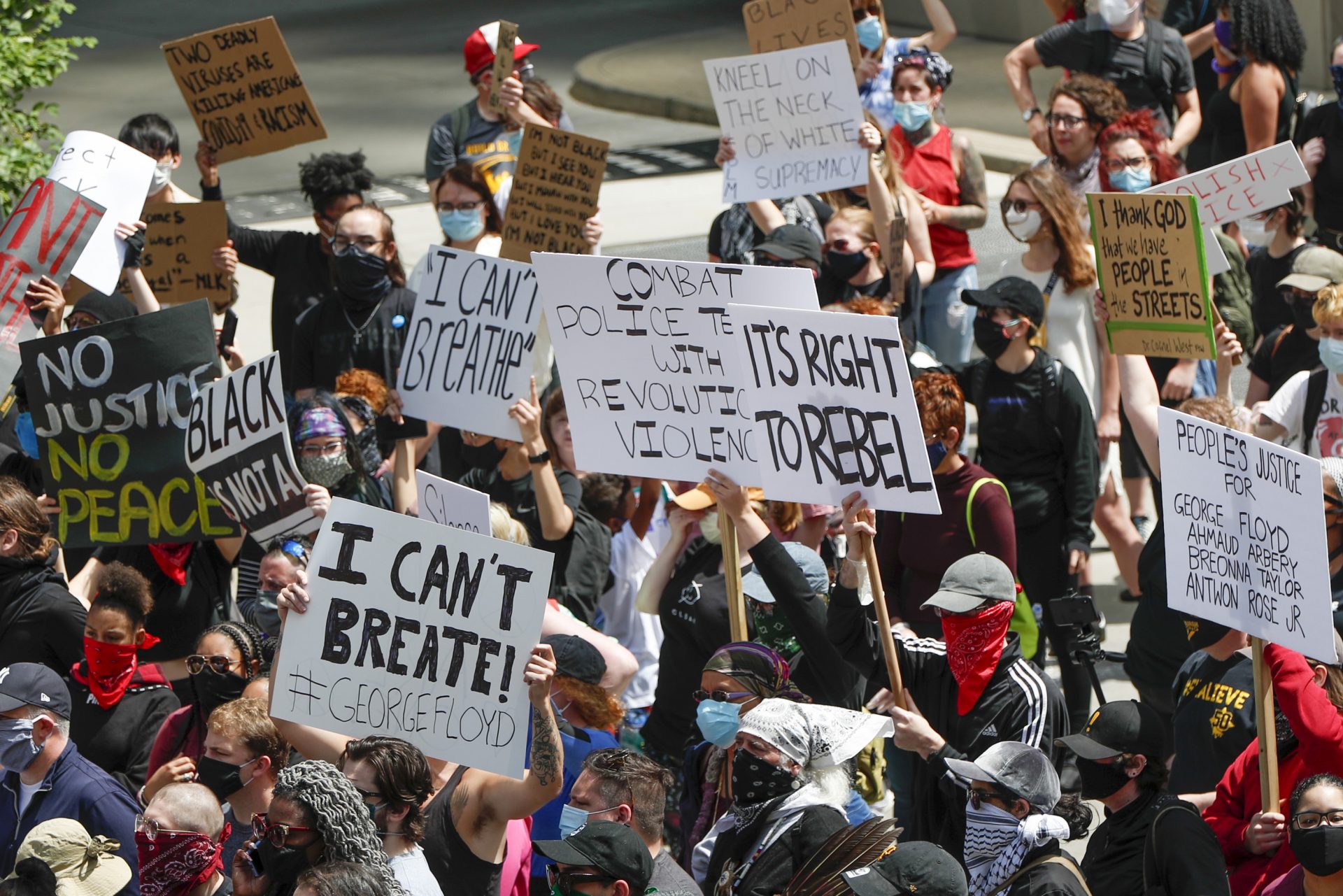 Demonstrators carry signs as they gather in a street during a march in Pittsburgh, Saturday, May 30, 2020 to protest the death of George Floyd, who died after being restrained by Minneapolis police officers on Memorial Day, May 25.