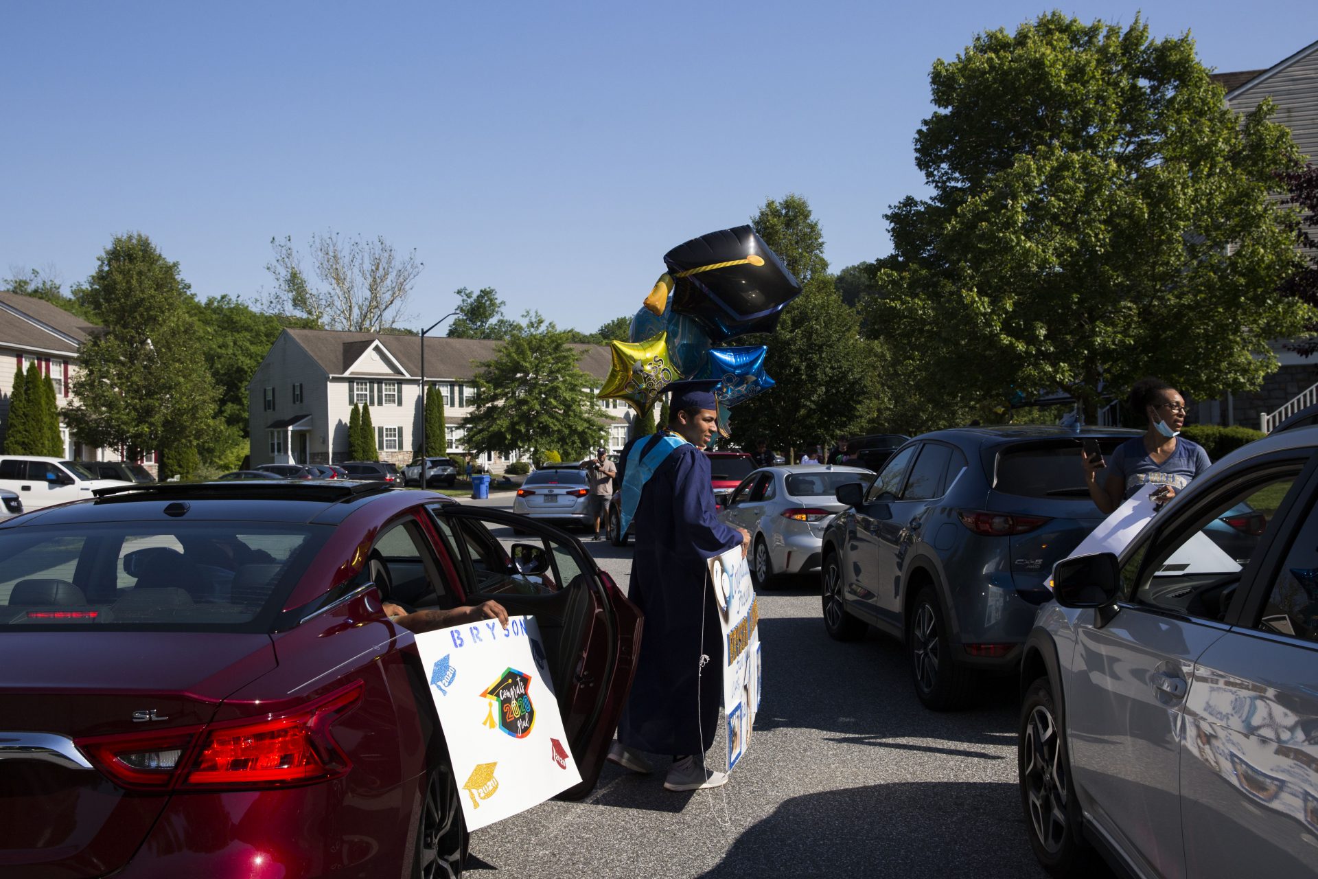 Bryson Eldridge (left) accepts balloons and a sign from a family member who attended his "drive by" graduation party on June 9, 2020.