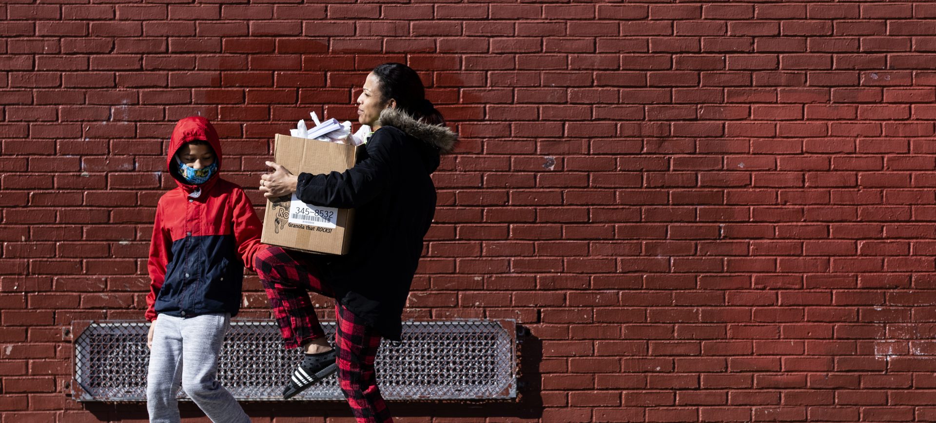 A woman carries a box of donated food and educational materials that she picked up at John H. Webster Elementary School in Philadelphia, Thursday, March 26, 2020. Gov. Tom Wolf’s administration reported more new coronavirus-related deaths in Pennsylvania on Wednesday. Residents are ordered to stay home, with few exceptions.