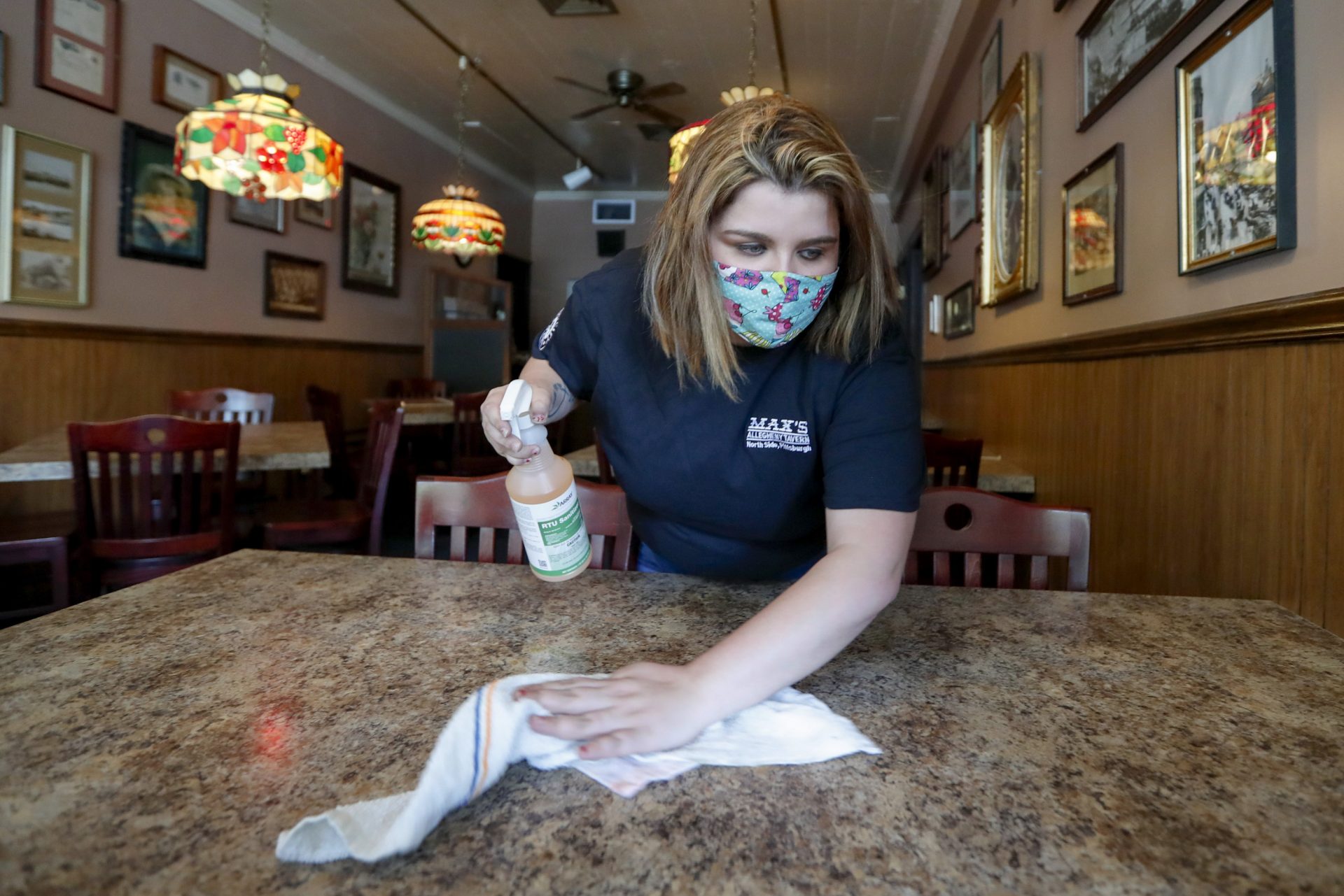 Sara Kennely, cleans one of the dining tables at Max's Allegheny Tavern, Thursday, June 4, 2020. The restaurant taped over the surfaces of some tables to restrict seating to maintain social distancing.