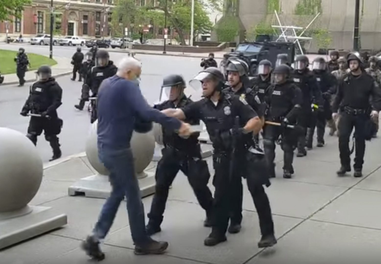 In this image from video provided by WBFO, a Buffalo police officer appears to shove a man who walked up to police Thursday, June 4, 2020, in Buffalo, N.Y. Video from WBFO shows the man appearing to hit his head on the pavement, with blood leaking out as officers walk past to clear Niagara Square. Buffalo police initially said in a statement that a person “was injured when he tripped & fell,” WIVB-TV reported, but Capt. Jeff Rinaldo later told the TV station that an internal affairs investigation was opened.