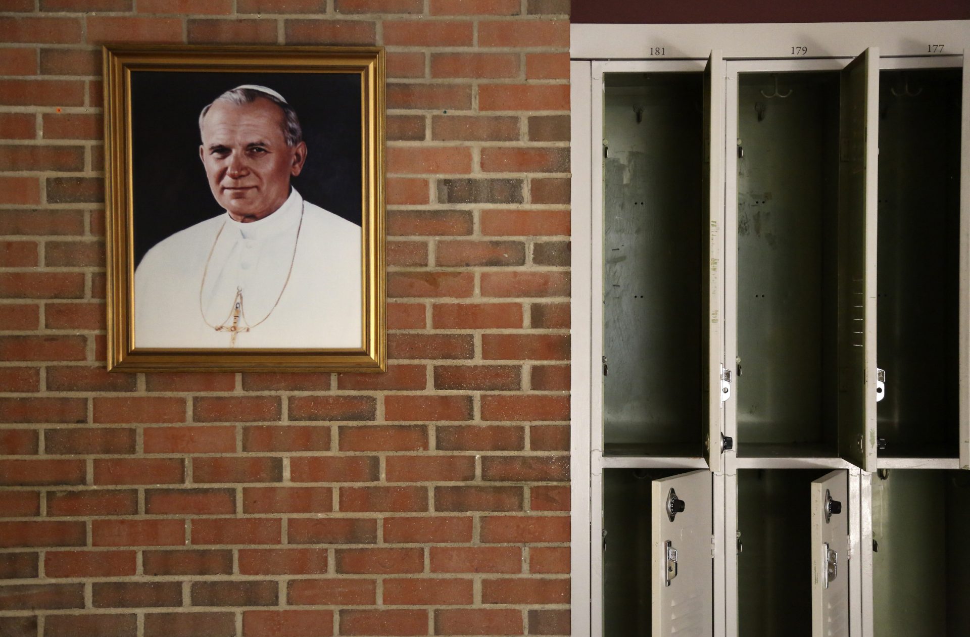 A portrait of St. John Paul II hangs beside a row of empty lockers in the main hallway of Quigley Catholic High School in Baden, Pa., Monday, June 8, 2020.