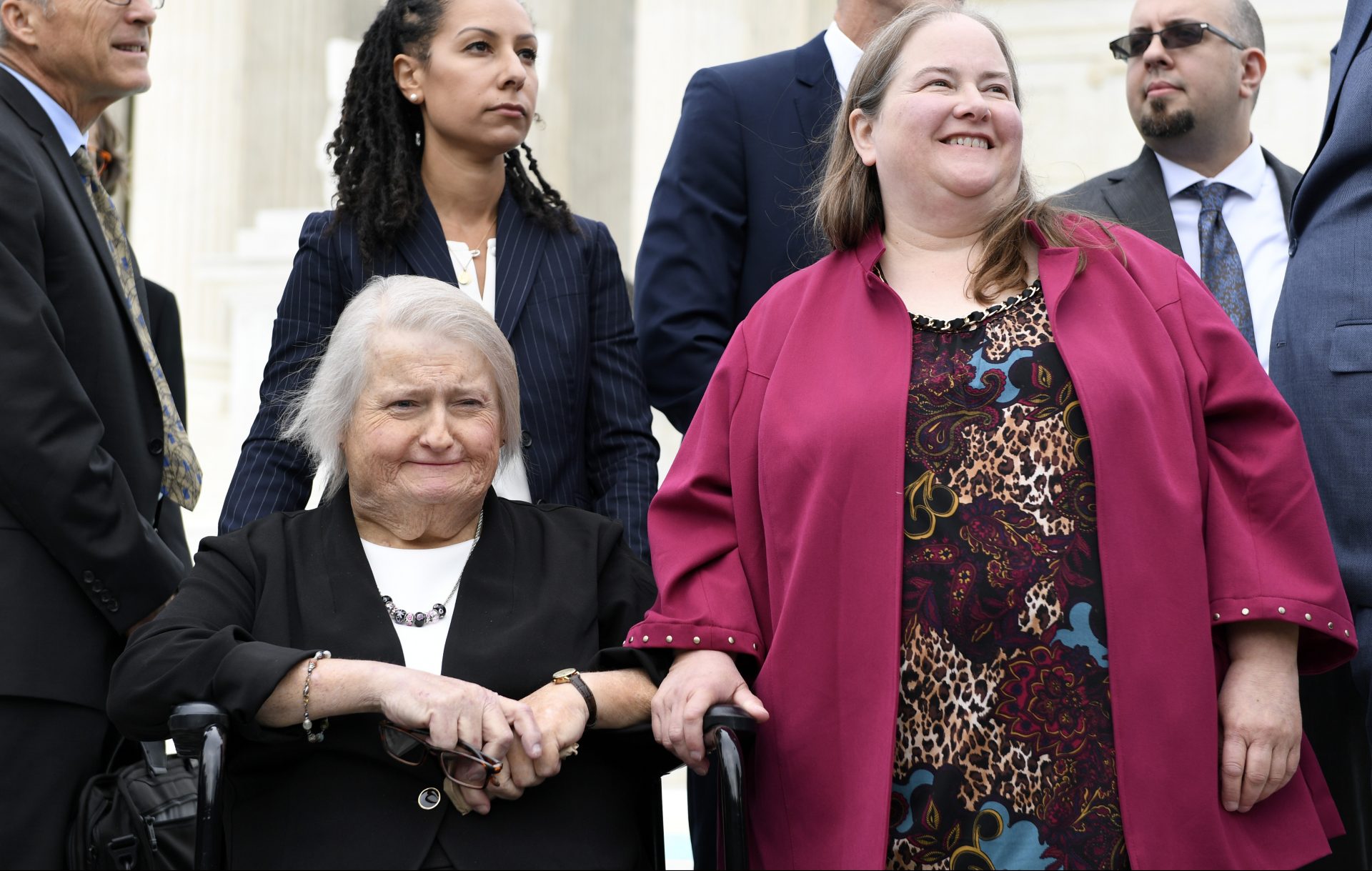 Aimee Stephens, seated, and her wife Donna Stephens, in pink, listen during a news conference outside the Supreme Court in Washington, Tuesday, Oct. 8, 2019. Aimee Stephens lost her job when she told Thomas Rost, owner of the Detroit-area R.G. and G.R. Harris Funeral Homes, that she had struggled with gender identity issues almost her whole life. The Supreme Court heard oral arguments earlier in the day on her case.
