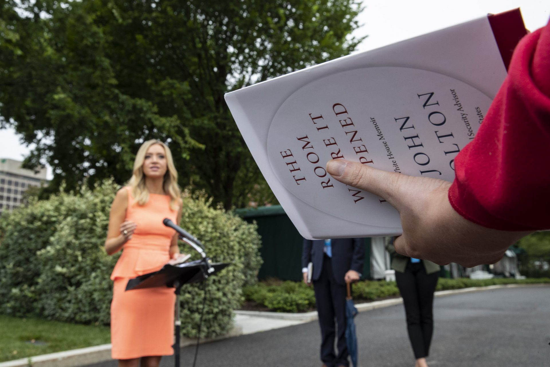 CBS White House correspondent Paula Reid, right, holds a copy of John Bolton's "The Room Where It Happened," as she asks a question of White House press secretary Kayleigh McEnany, at the White House, Thursday, June 18, 2020, in Washington.