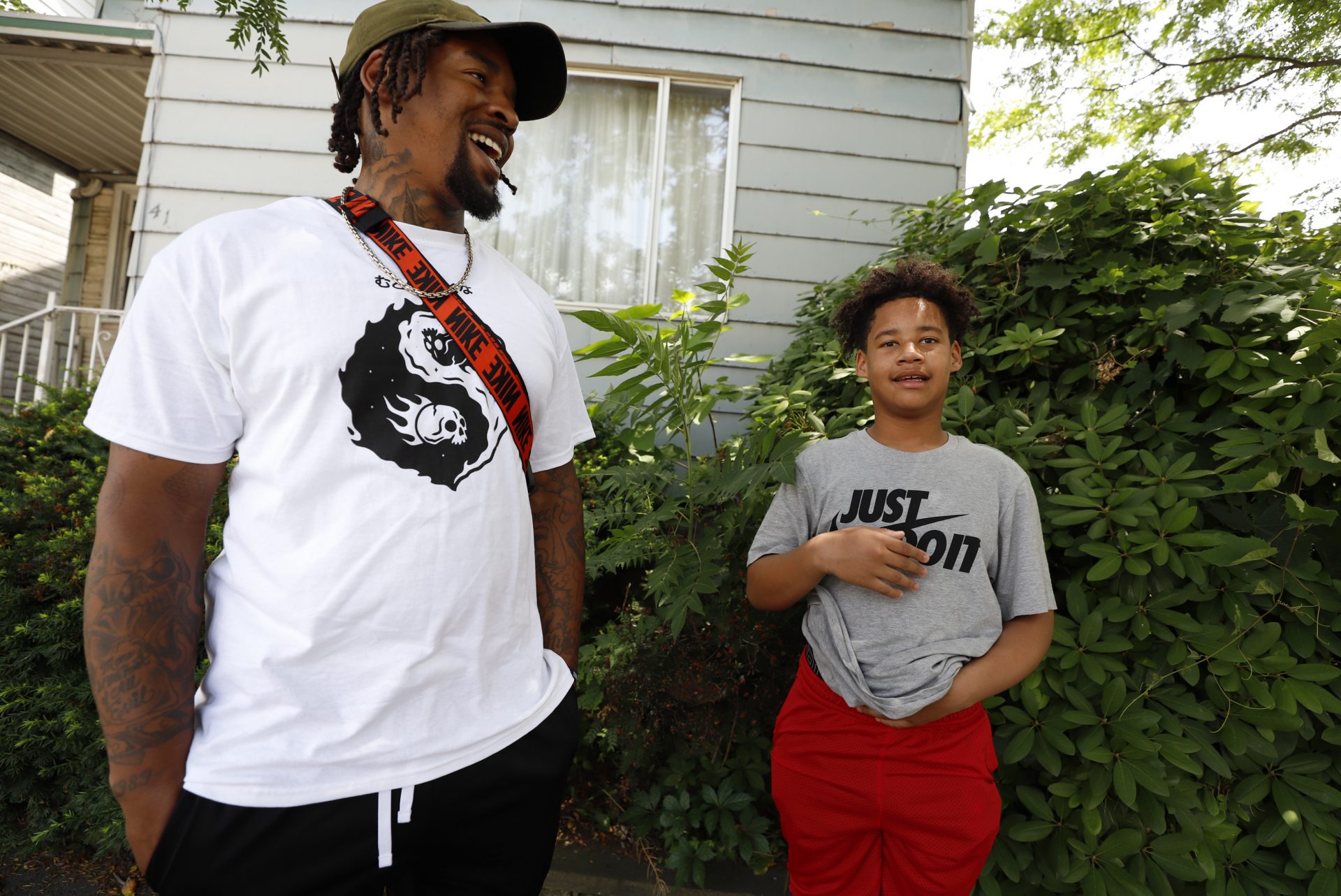 Daylan McLee, left and son Avian, 13, stand on the sidewalk in front of their home in Uniontown, Pa., Monday, June 22, 2020. On Sunday McLee helped pull Uniontown Police Officer Jay Hanley from his burning patrol car following a collision.