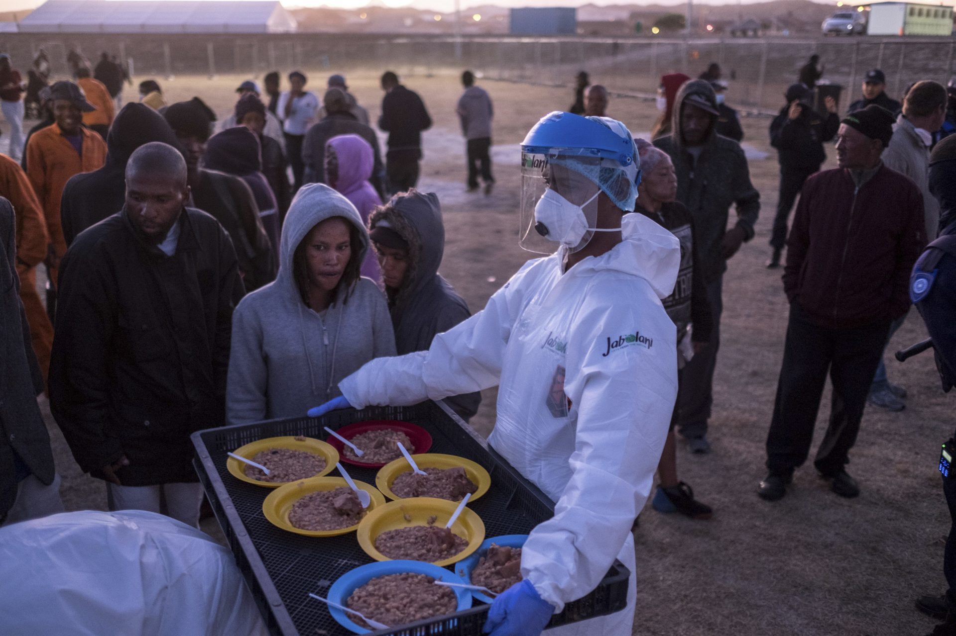 People receive food at a camp set up to house them during the coronavirus lockdown in Cape Town. Many are unhappy with the conditions of their confinement and worry that overcrowding poses a risk of catching the virus.