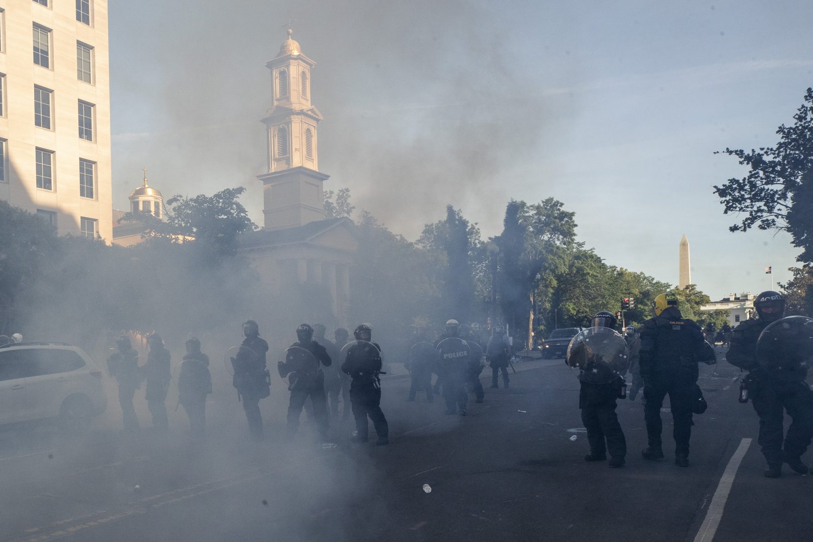 Tear gas floats in the air as a line of police move demonstrators away from St. John's Church across Lafayette Park from the White House, as they gather to protest the death of George Floyd, Monday, June 1, 2020, in Washington. Floyd died after being restrained by Minneapolis police officers.