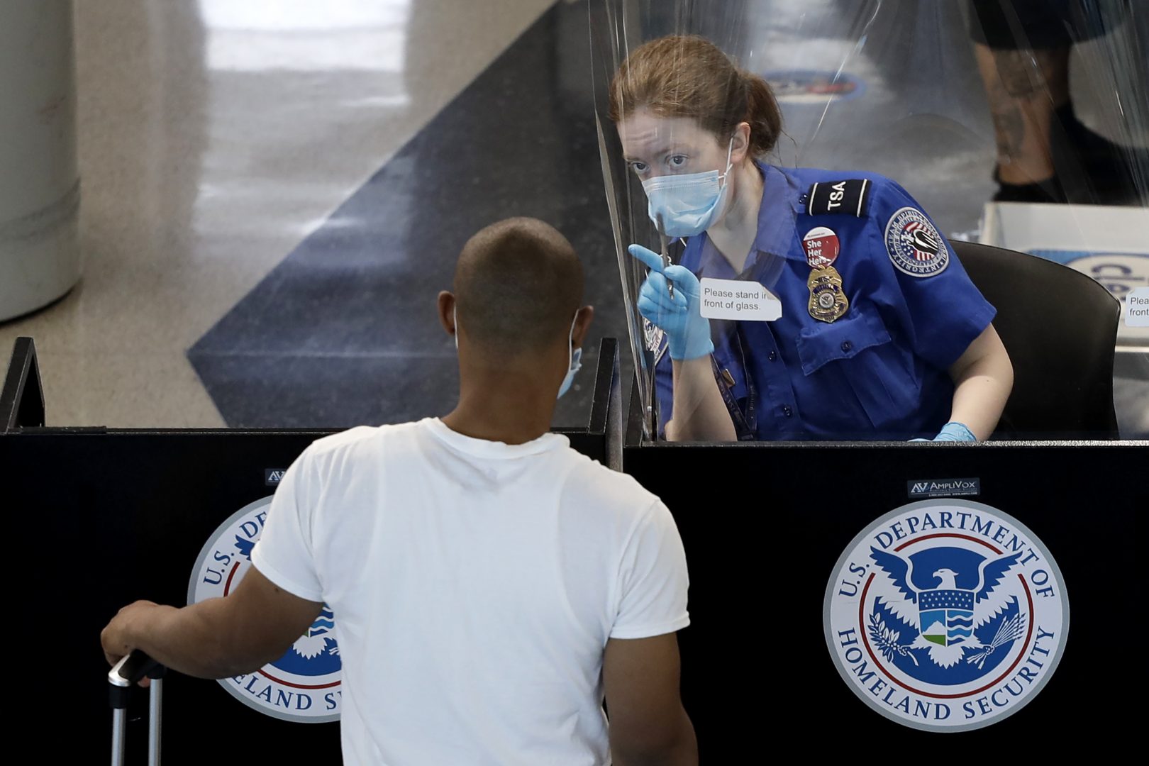 A Transportation Security Administration officer, right, talks with a passenger at a security checkpoint in O'Hare International Airport, Tuesday, June 16, 2020, in Chicago. Beginning June 16 at American Airlines and June 18 at United Airlines, all passengers and crew members will be required to wear masks to prevent the spread of the coronavirus. (AP Photo/Nam Y. Huh)